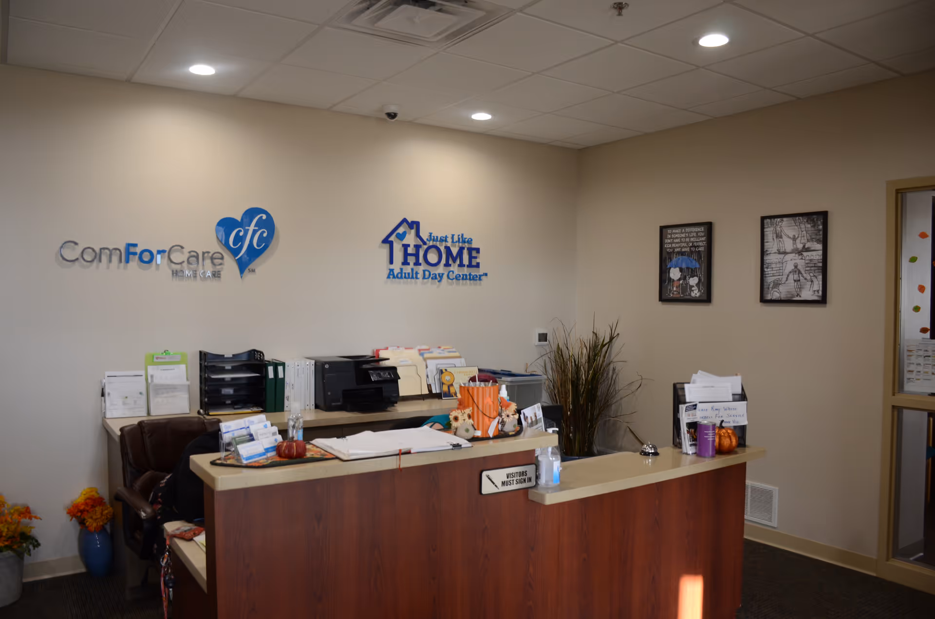 Reception desk in a neutral lobby with Just Like Home and ComForCare signage on the wall