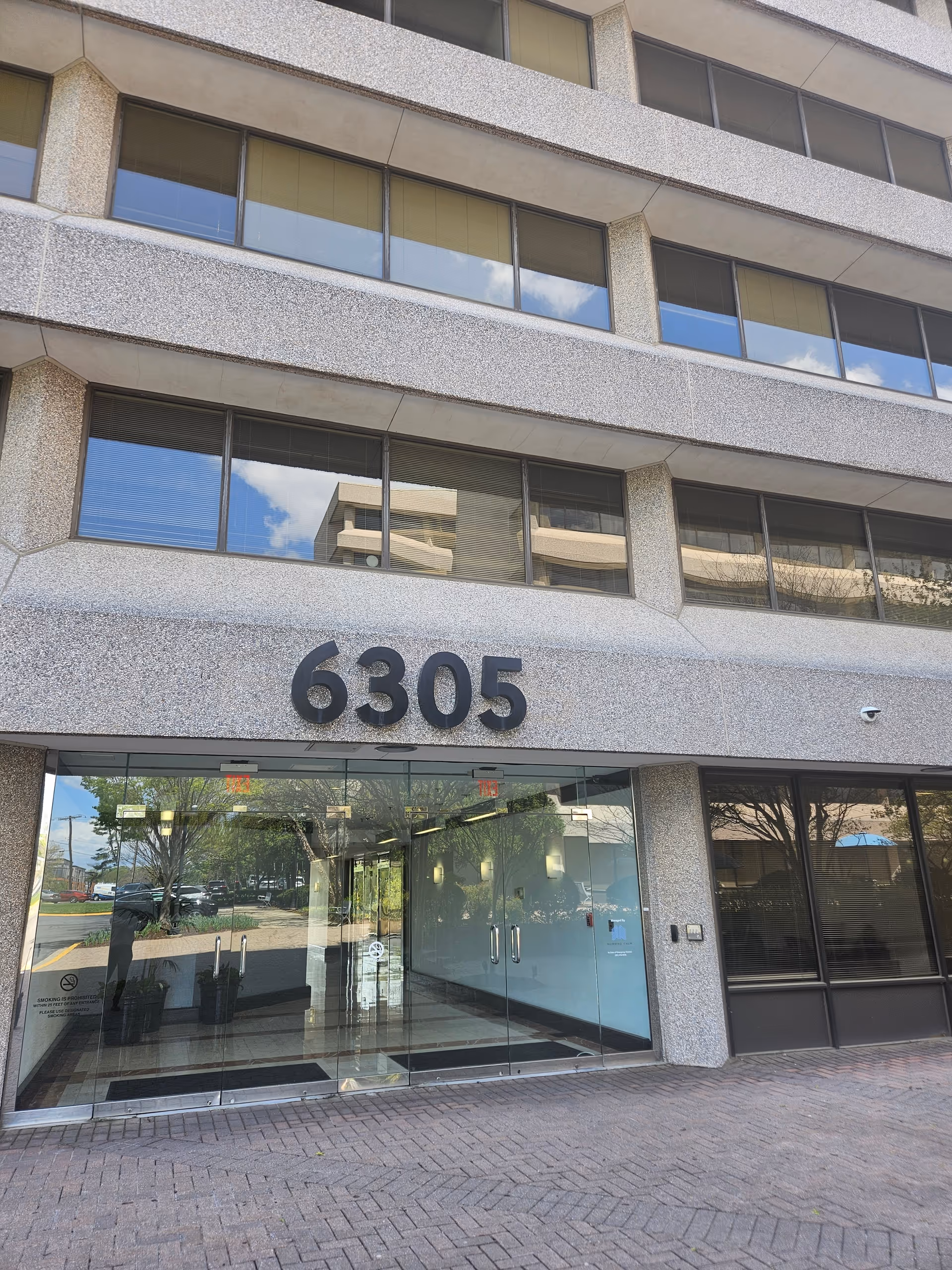 Modern office building entrance with glass doors and large 6305 numerals.