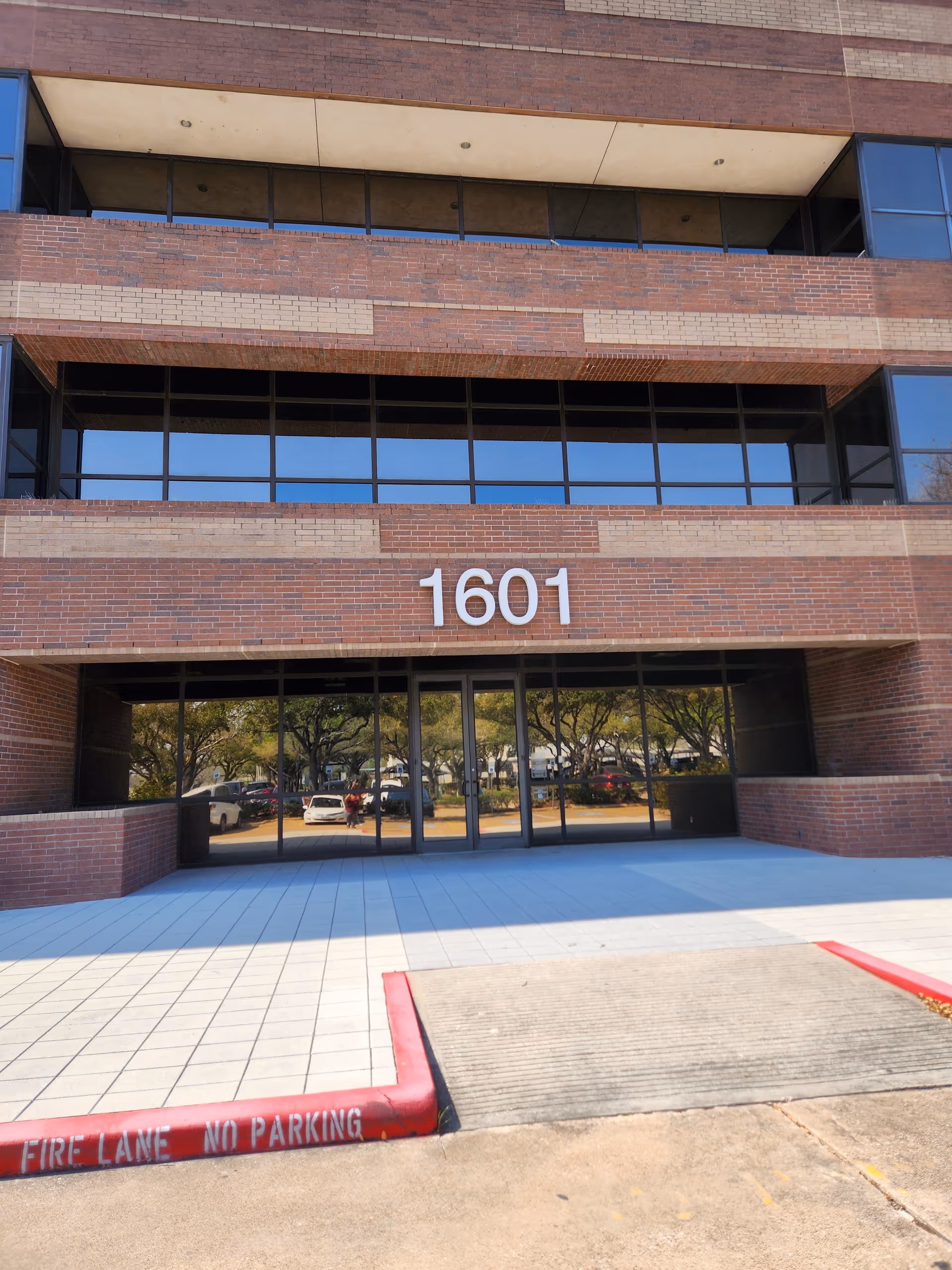 Brick building exterior with large glass entrance and the number 1601 displayed prominently.