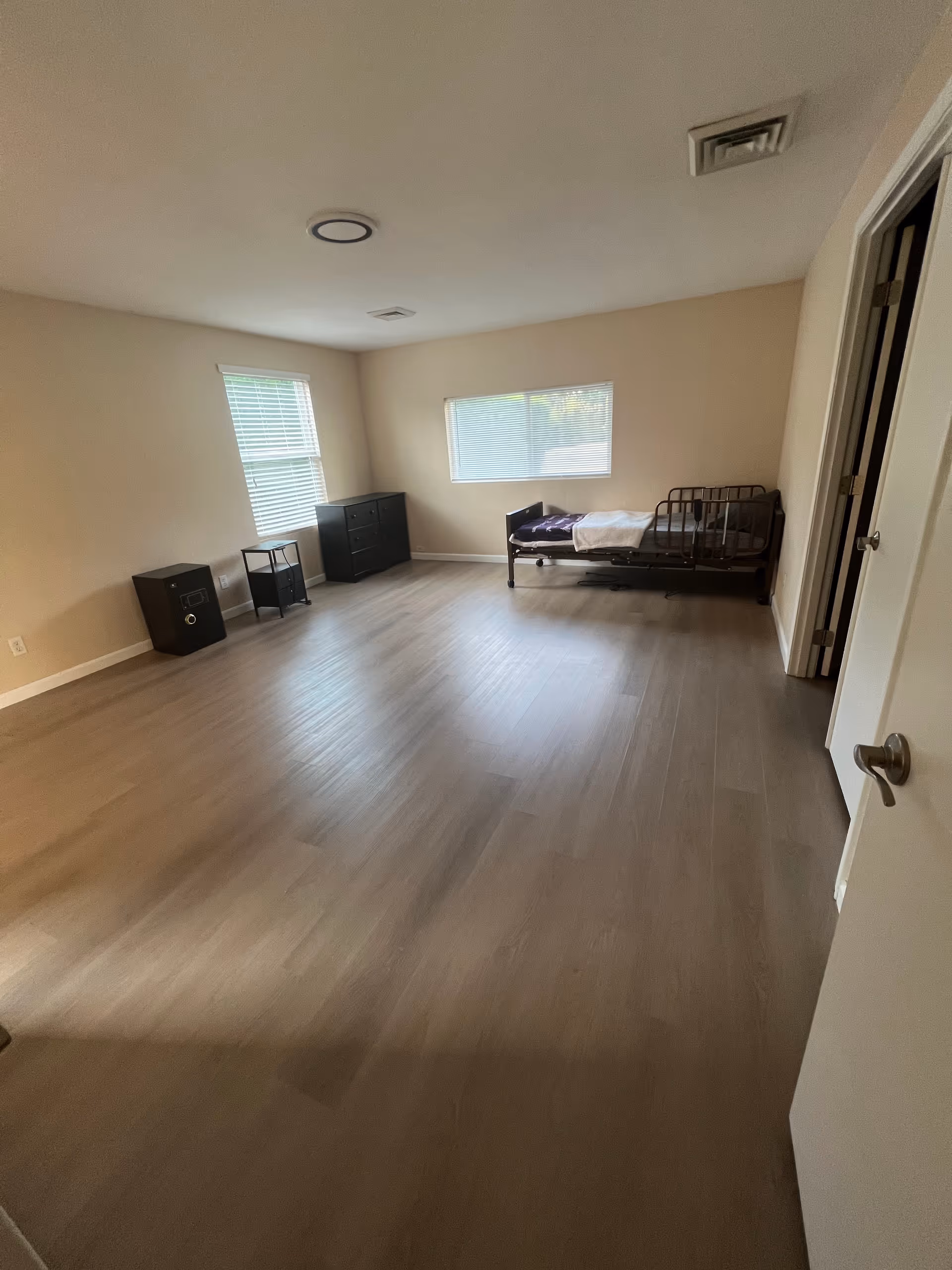Sparsely furnished bedroom in a senior living facility with bed and dresser