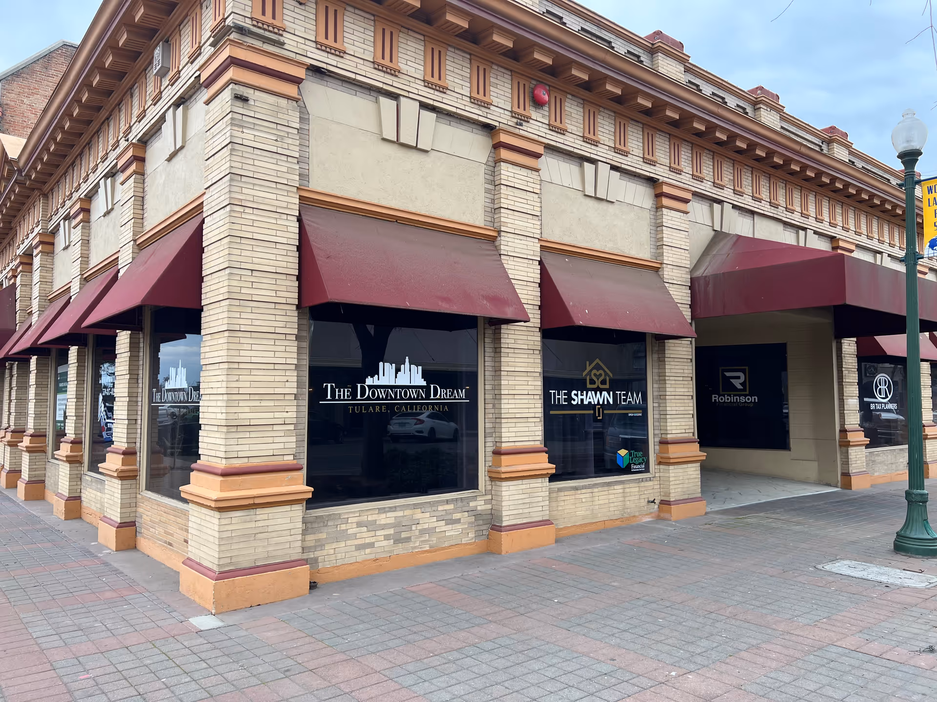 Exterior brick storefronts with maroon awnings and large display windows.
