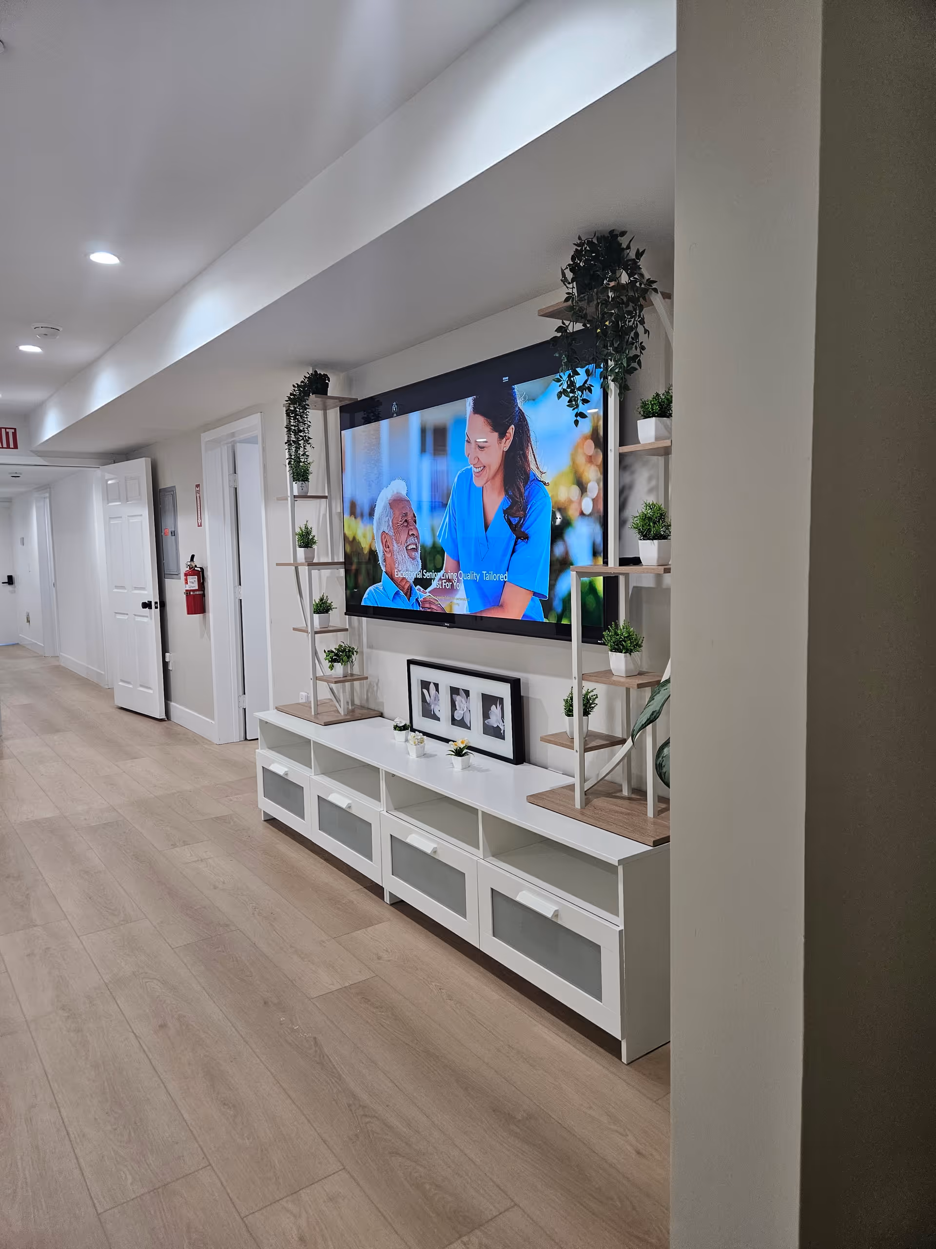 Kingston Care Living hallway featuring a mounted TV and white storage console with plants