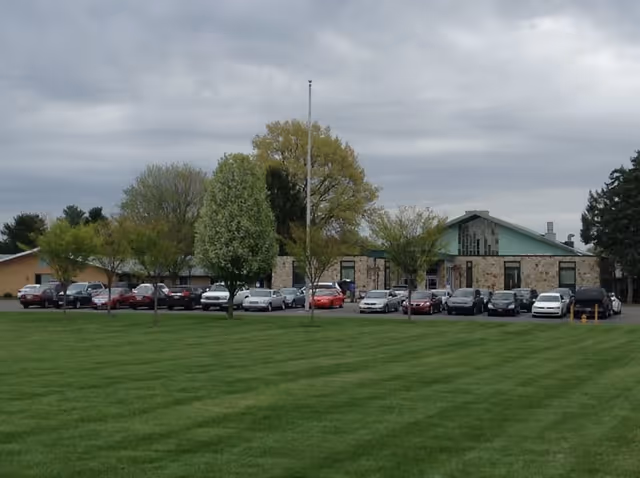Exterior view of Lancashire Hall with a long row of parked cars and green lawn.