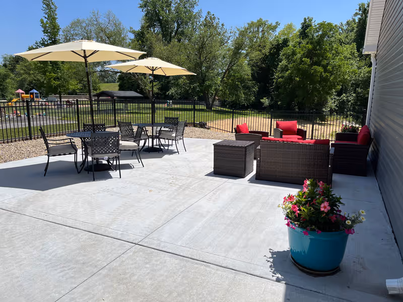 Outdoor patio with tables, umbrellas, and red cushioned seating at Aspen Valley Senior Home