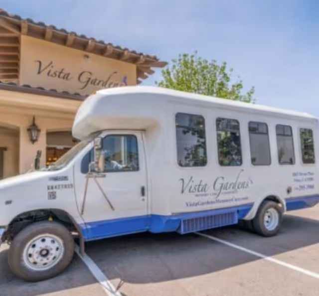 Front view of Vista Gardens Memory Care with a parked bus in the driveway.