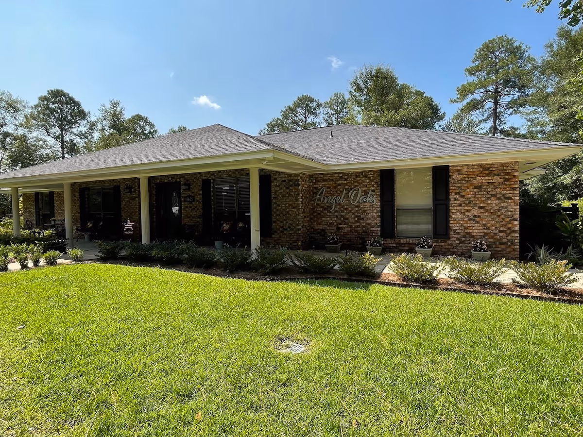 Single-story brick senior living building with a covered entrance and landscaped front lawn.