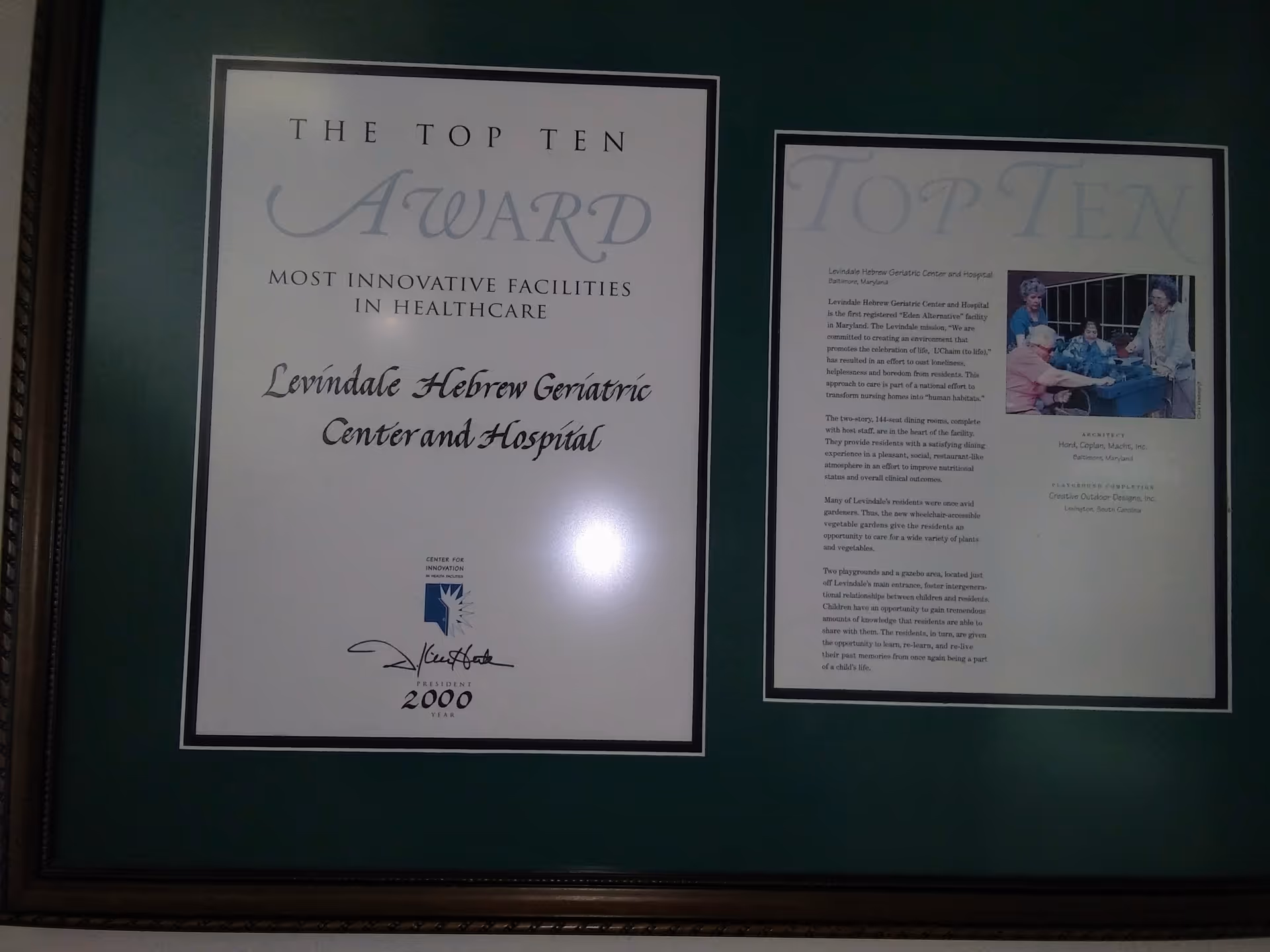 Two framed award plaques on a dark green interior wall.