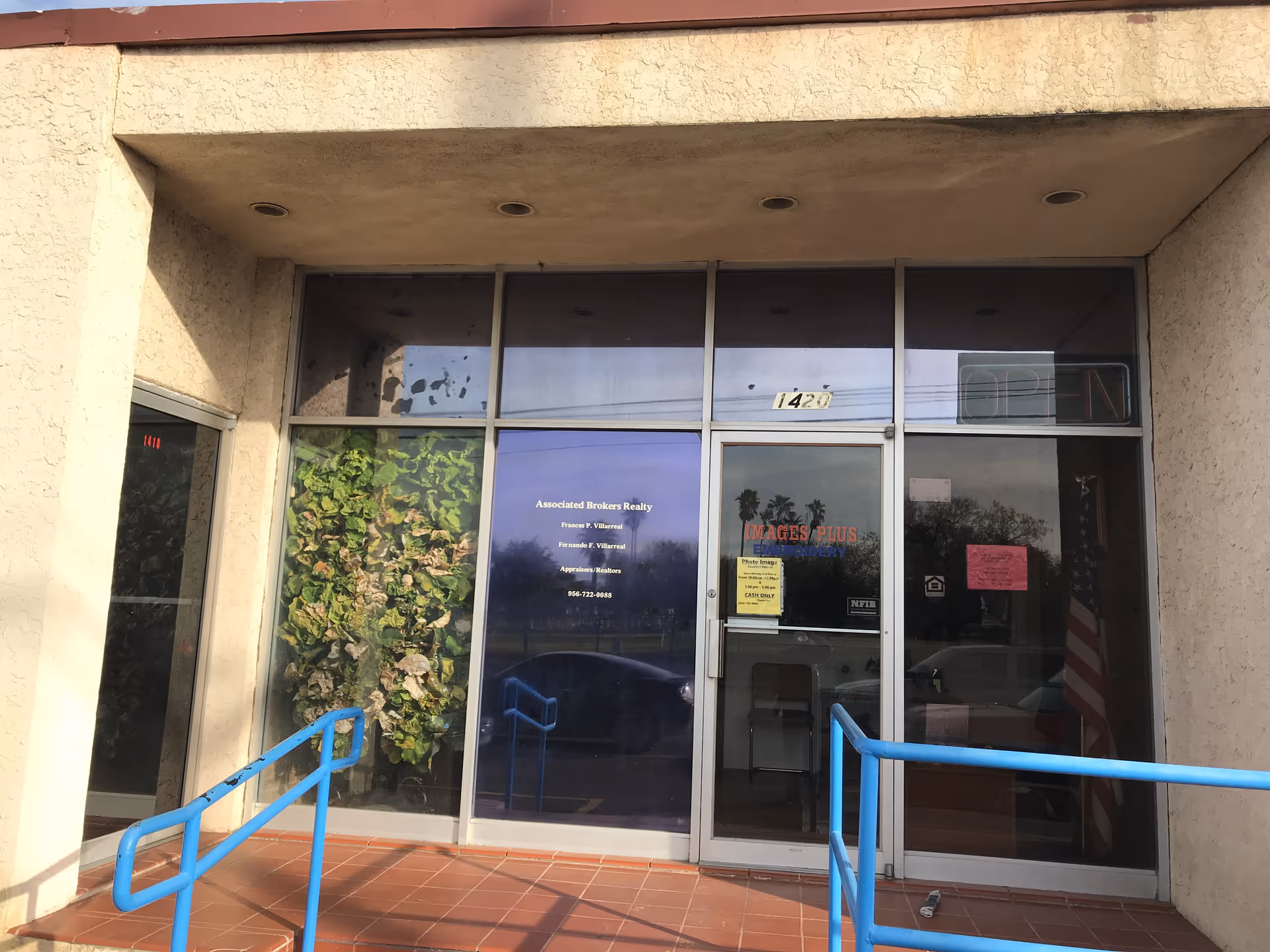 Exterior view of a facility entrance with glass doors and blue railings.