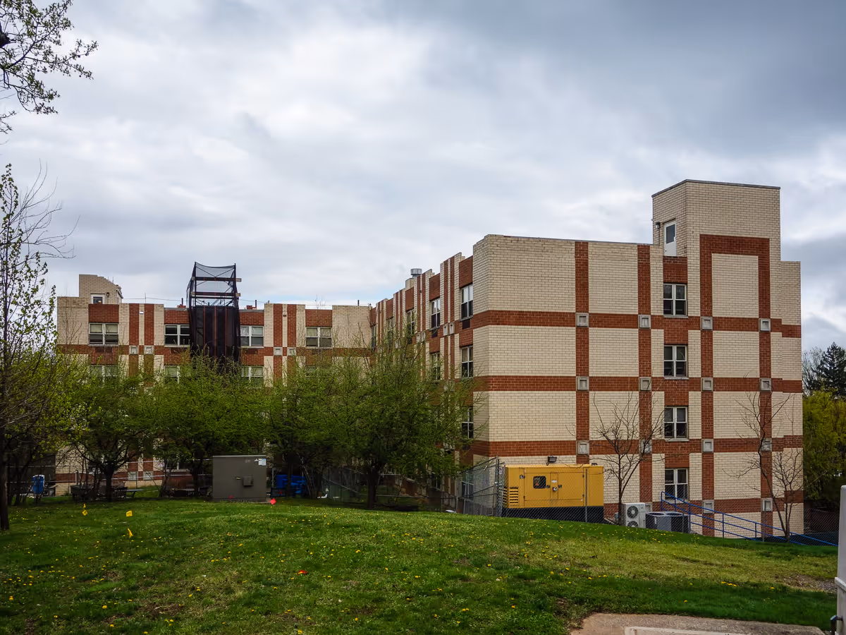 Exterior view of a brick senior living facility with trees and grassy foreground