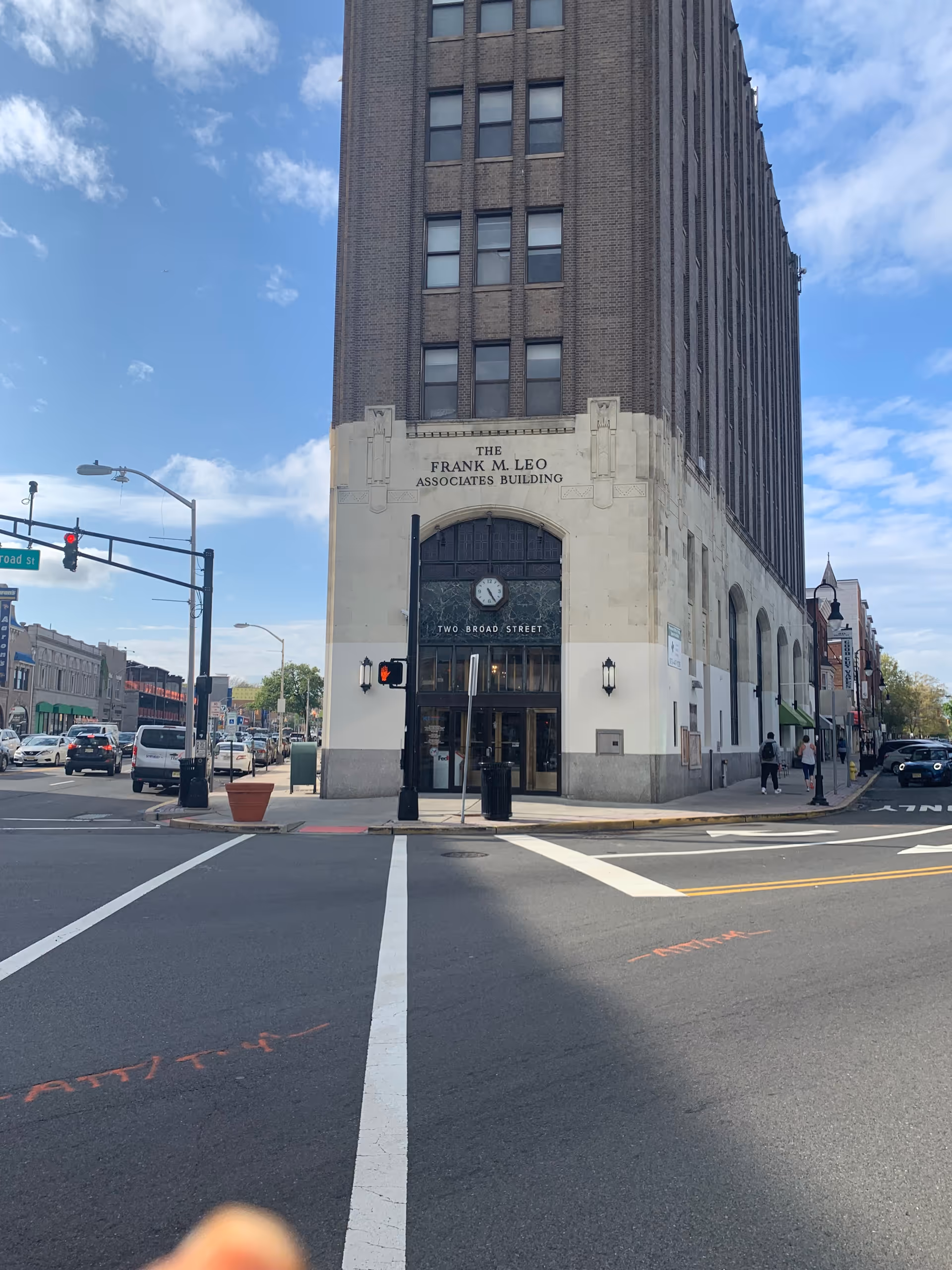 Tall brick building at a busy intersection with arched entrance and clock.