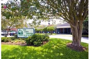 Exterior view of The Care Center with a sign, a lawn, and large trees.