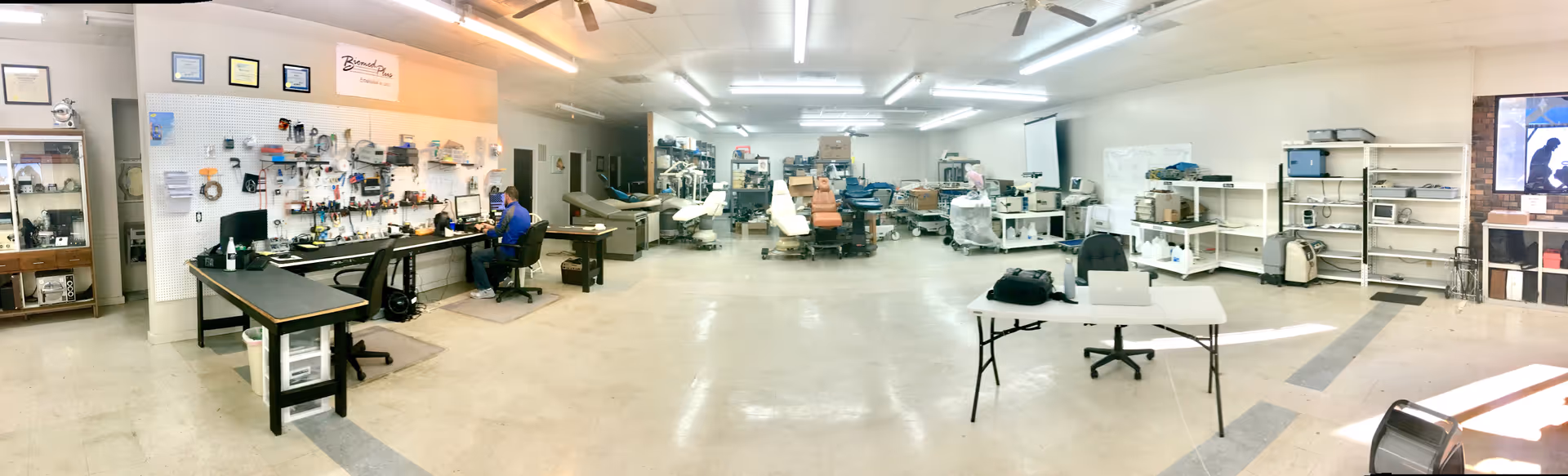 Wide interior of a Biomed Plus workshop featuring workstations, tools, and medical equipment.