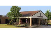 Exterior view of Saint John XXIII Home with entrance, trees, and lawn.