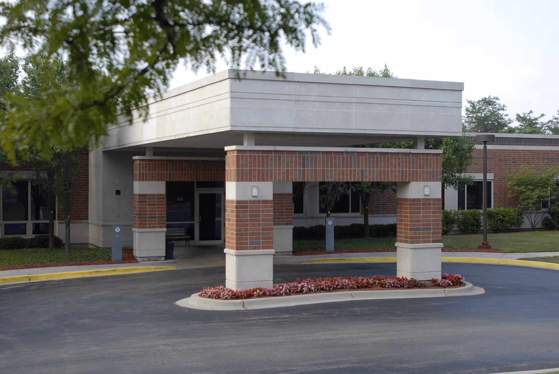 Front view of Weinberg Community for Senior Living entrance with brick pillars and a driveway canopy