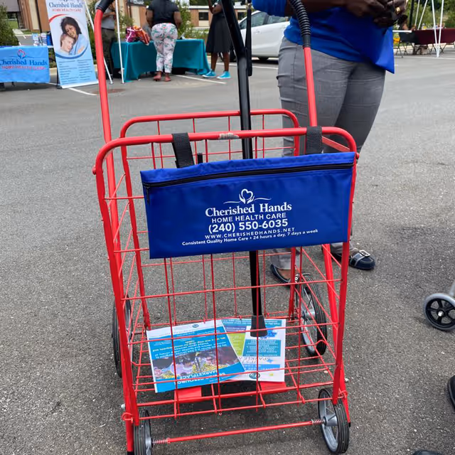 Red promotional cart with Cherished Hands Home Health Care banner at an outdoor event.