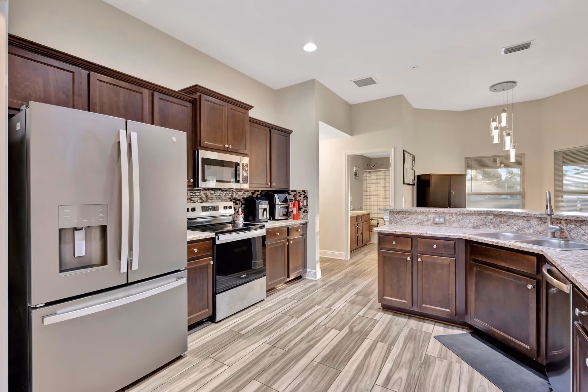 Modern kitchen with stainless appliances, dark wood cabinets, and a curved island.