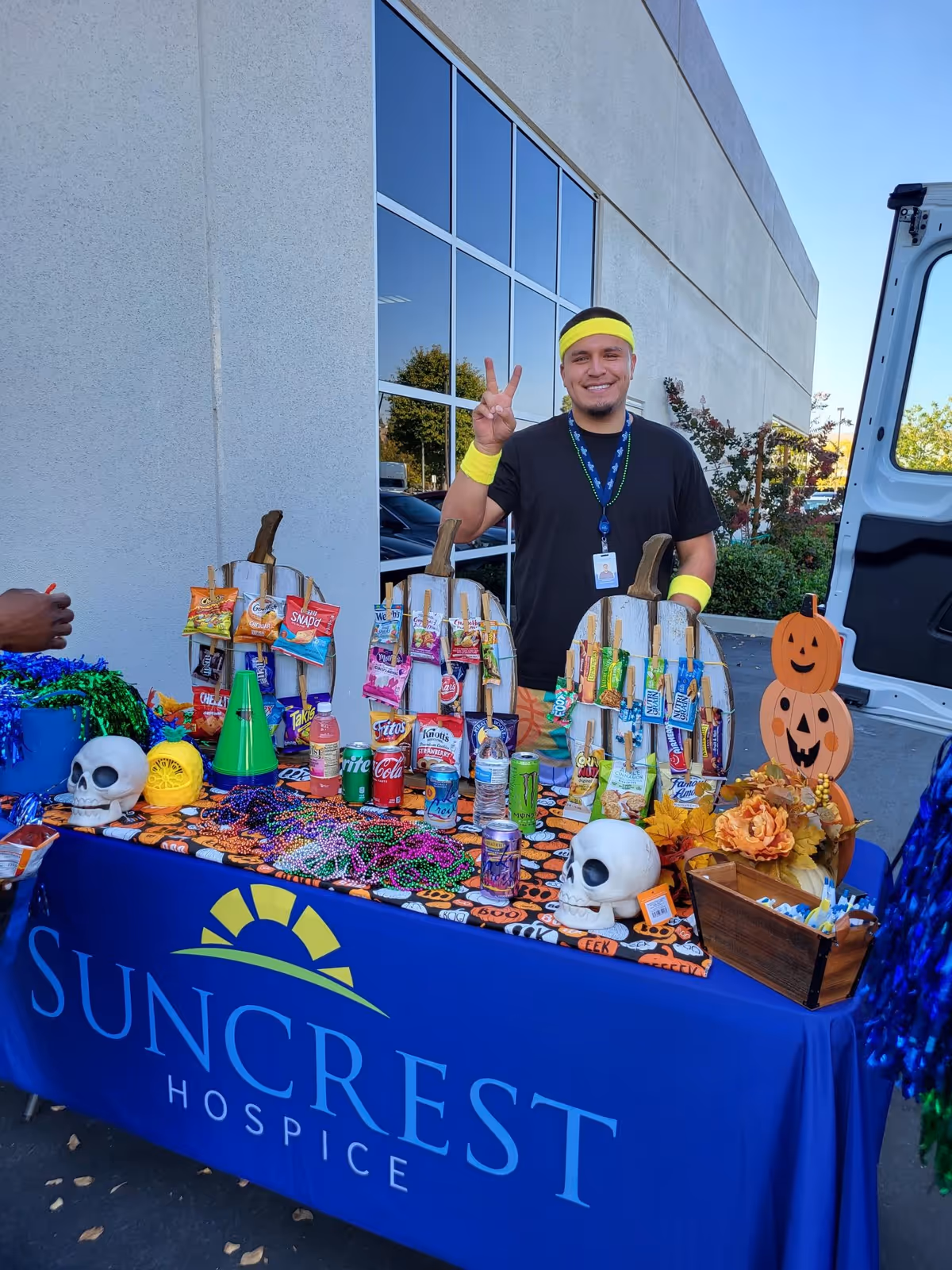 Staff member poses beside a decorated outdoor Suncrest Hospice table with snacks and Halloween decor.