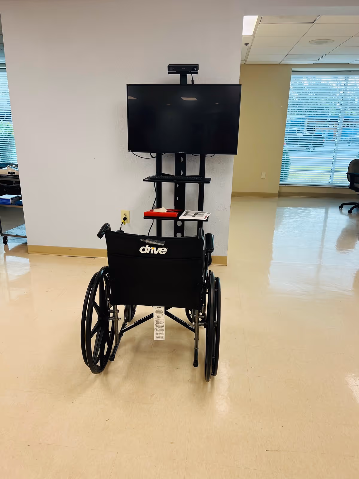 Wheelchair faces a wall-mounted TV on a stand inside Bayshore Pointe Nursing and Rehab Center.