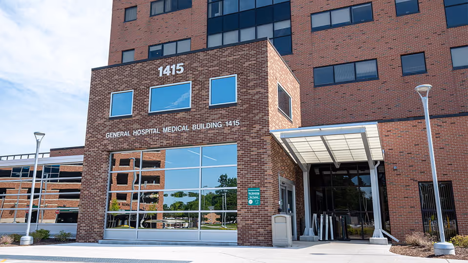 Brick general hospital building entrance with glass windows and a covered doorway.