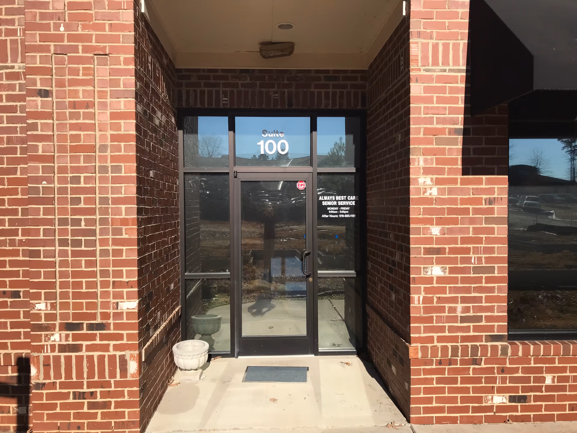 Brick exterior entrance with glass doors labeled Suite 100 for Always Best Care.