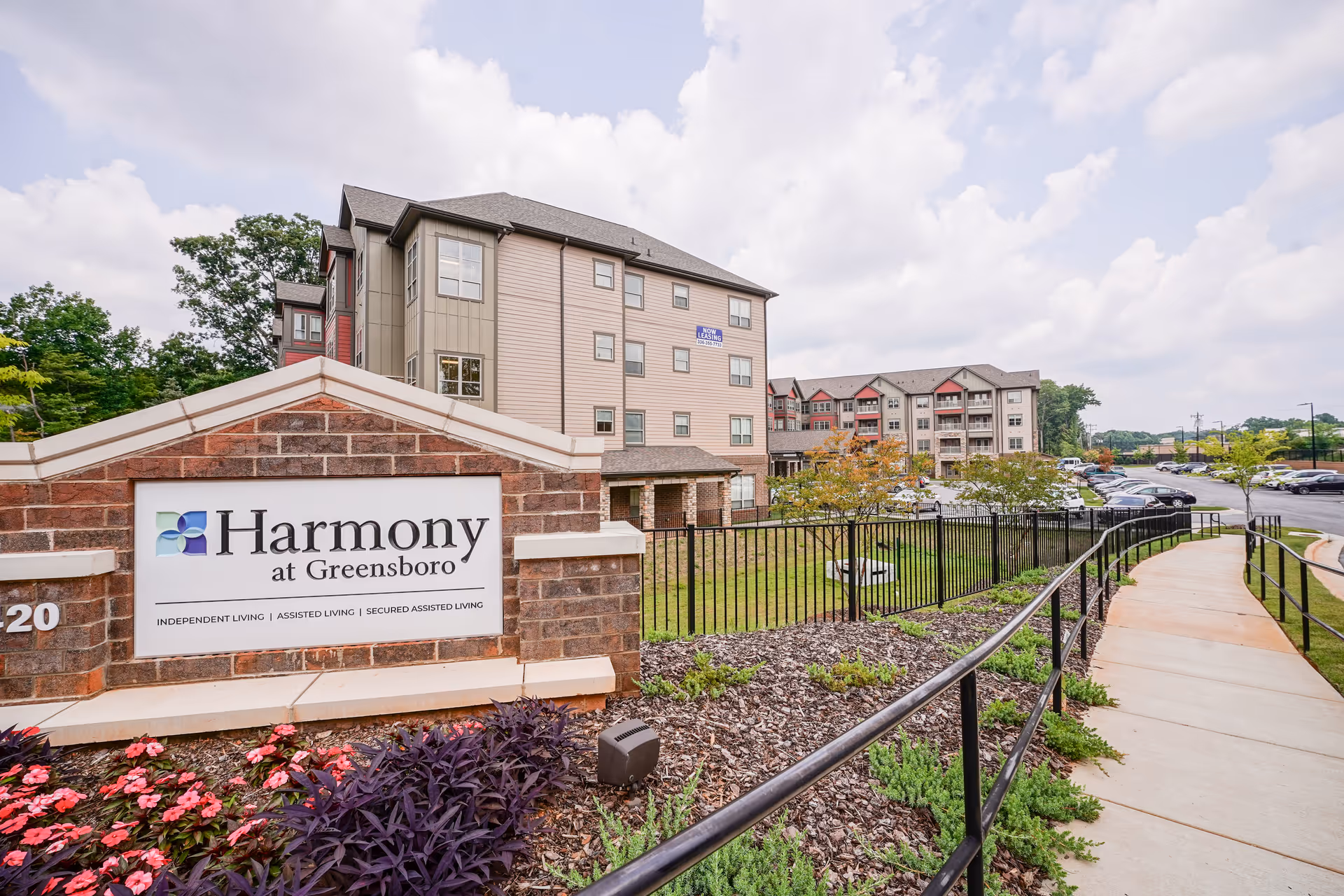 Exterior view of Harmony at Greensboro with sign, curved walkway, and multi-building campus.