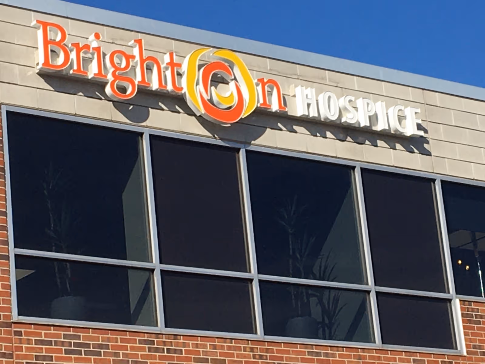 Exterior view of Brighton Hospice building with large windows and sign.