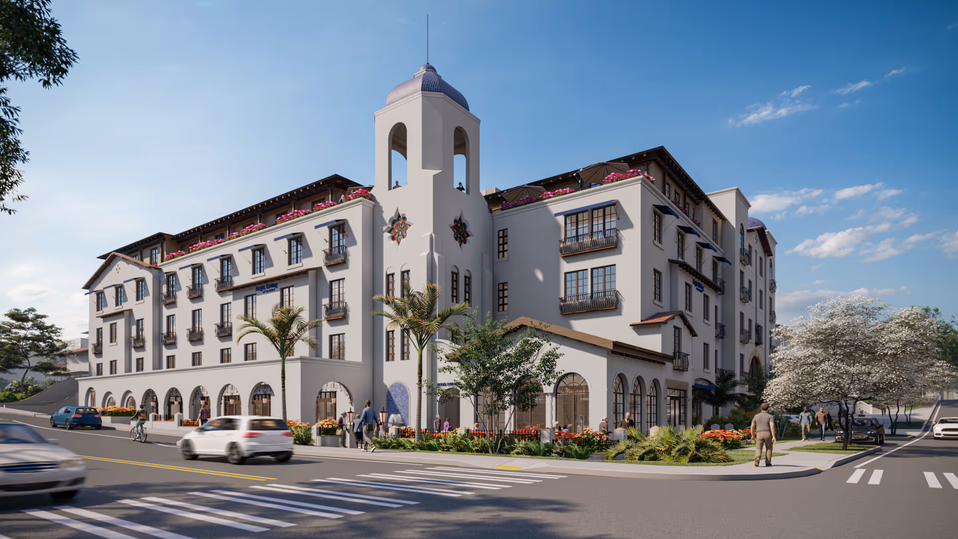 Exterior view of a multi-story senior living facility with Mediterranean architectural style, featuring arched windows, balconies with flower boxes, a central tower, palm trees, and landscaped greenery. People are walking on the sidewalks and cars are driving on the street in front of the building under a clear blue sky.
