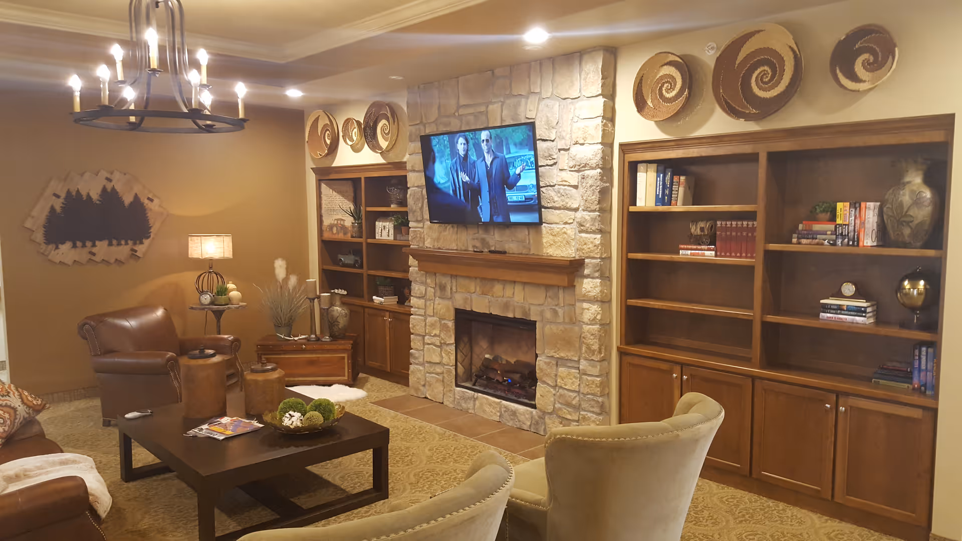 Cozy living room with stone fireplace, built-in shelves, TV, and plush seating.