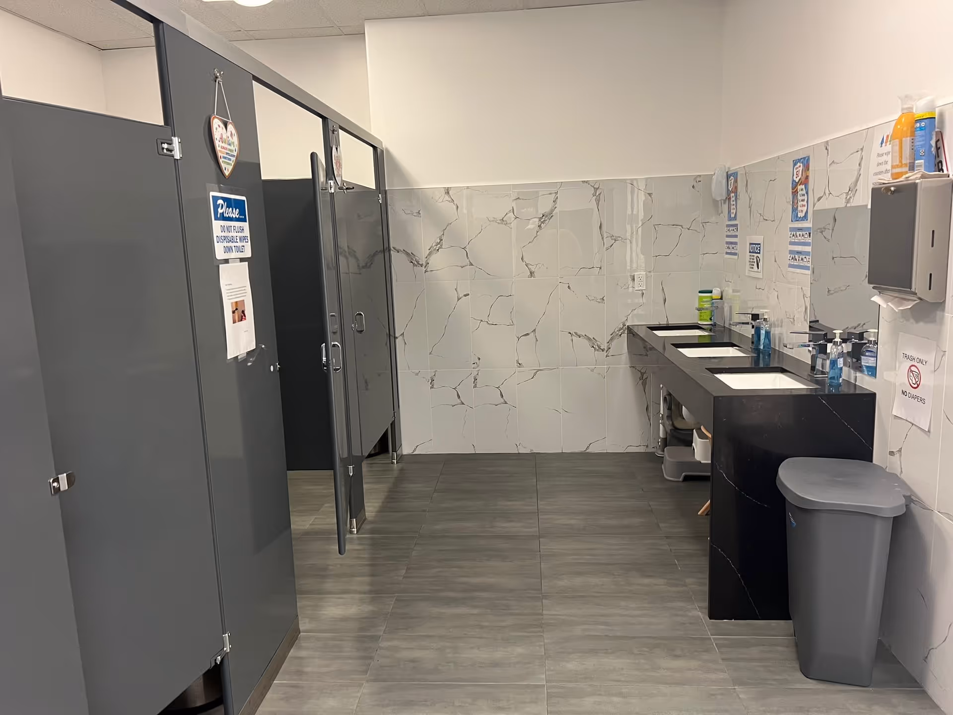 Public restroom with stalls, sinks, and tiled walls in a facility.