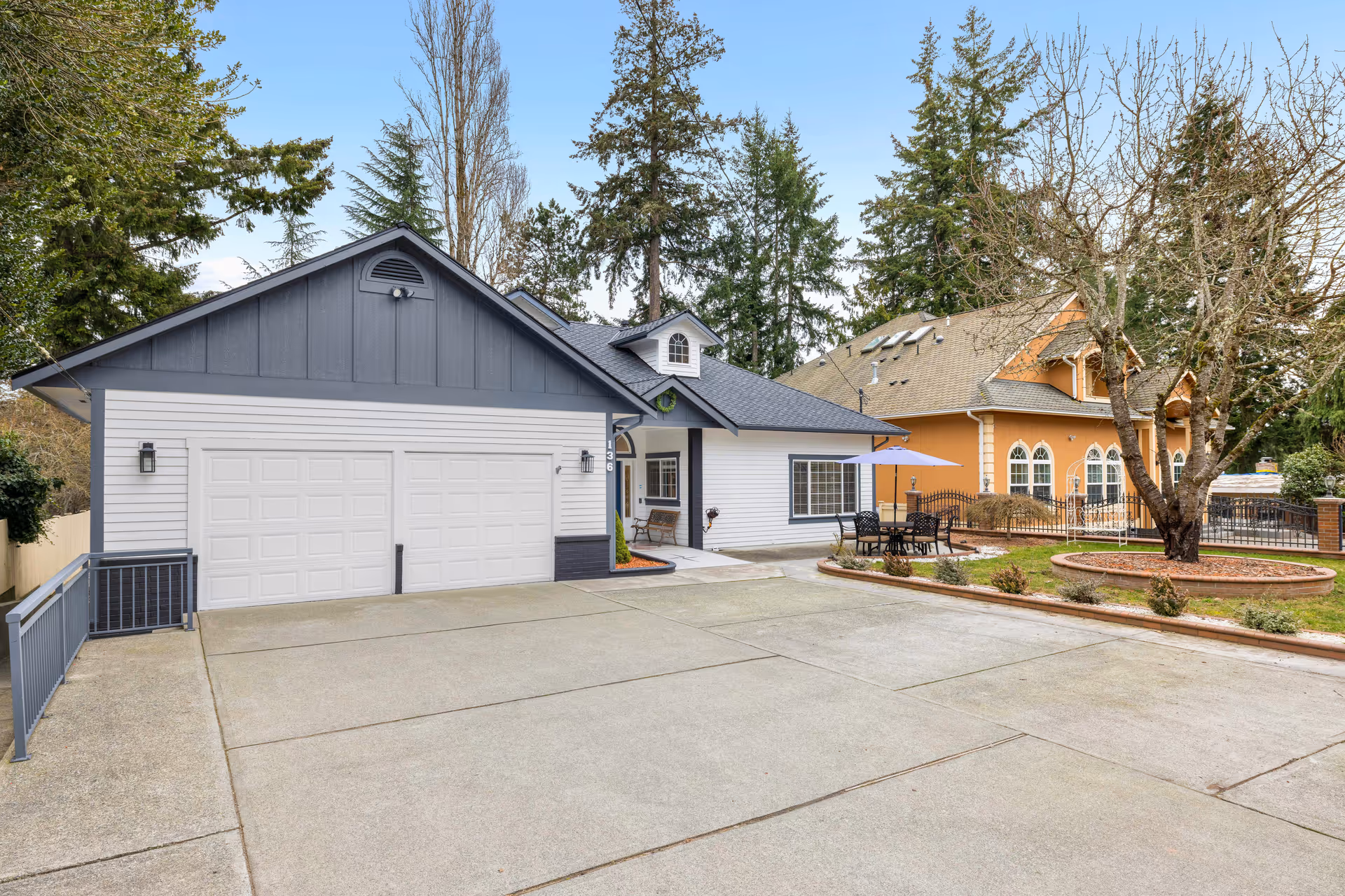 Exterior view of a building with a large driveway, garages, and outdoor seating.