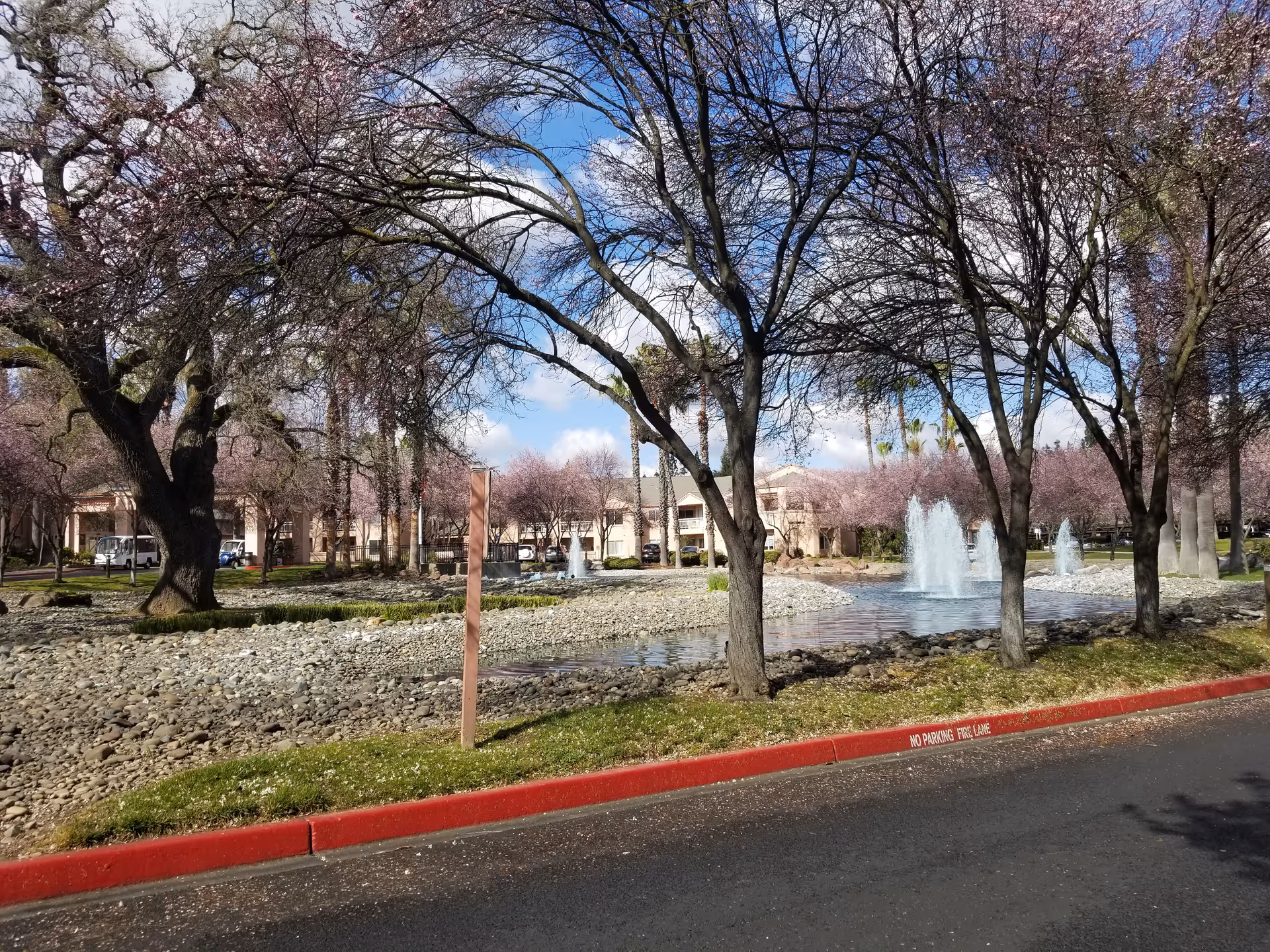 Exterior view of Eskaton Village Carmichael Care Center with trees and a fountain.