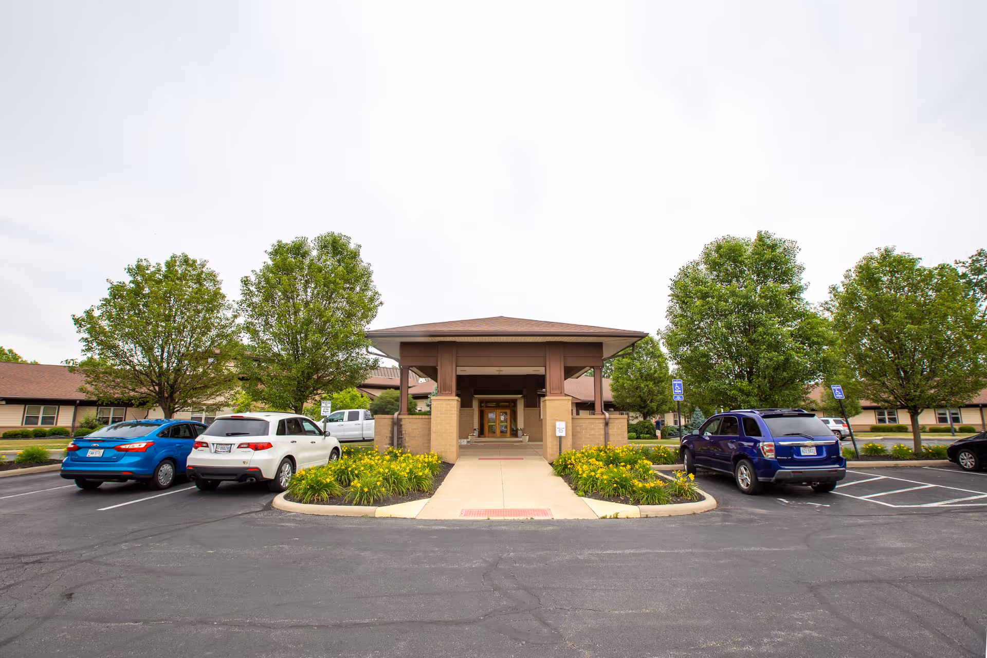 Front entrance of Altercare Hilliard senior living facility with a parking lot and trees