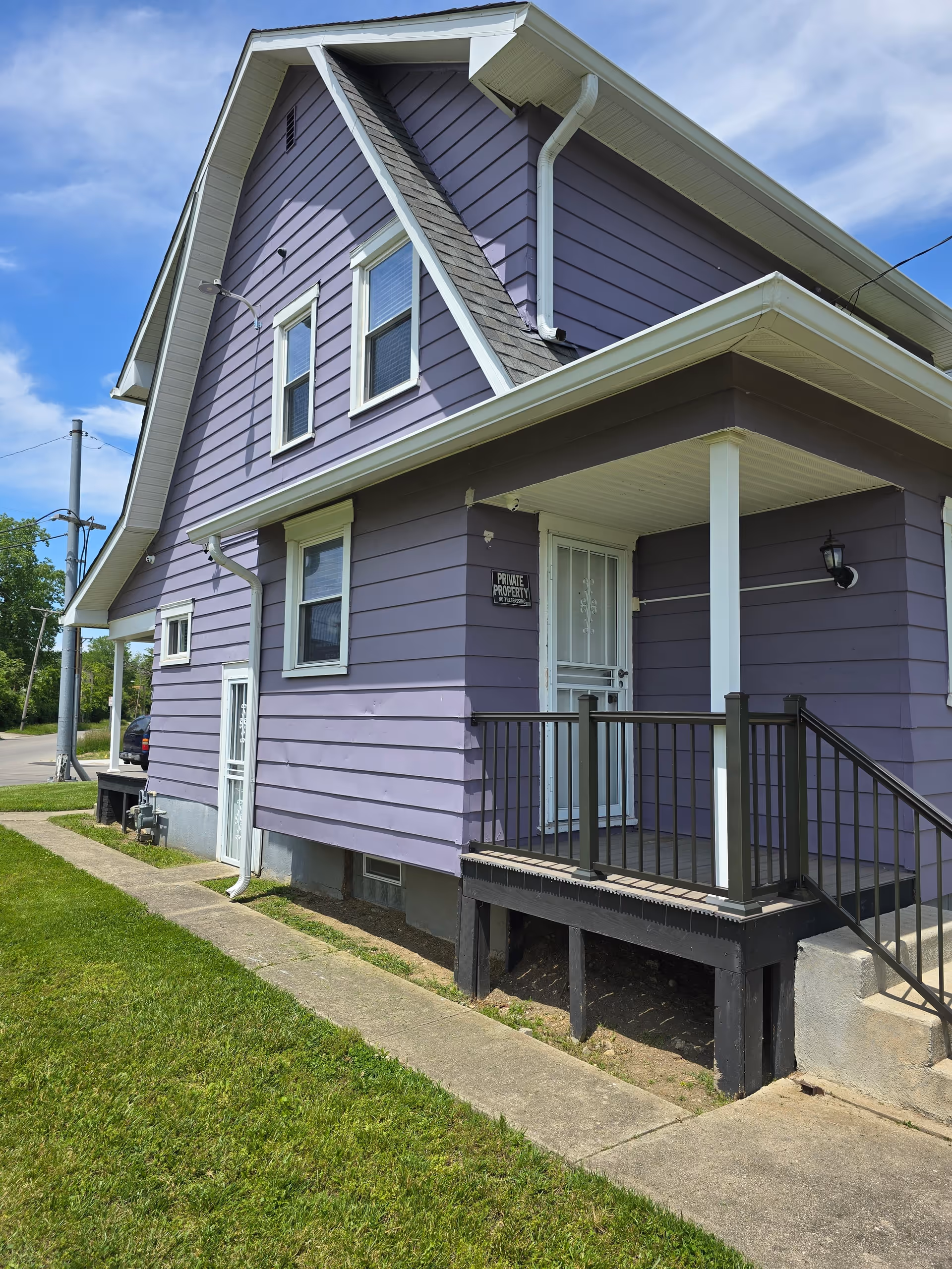 Purple two-story house with a small front porch, white trim, and a 'Private Property' sign.
