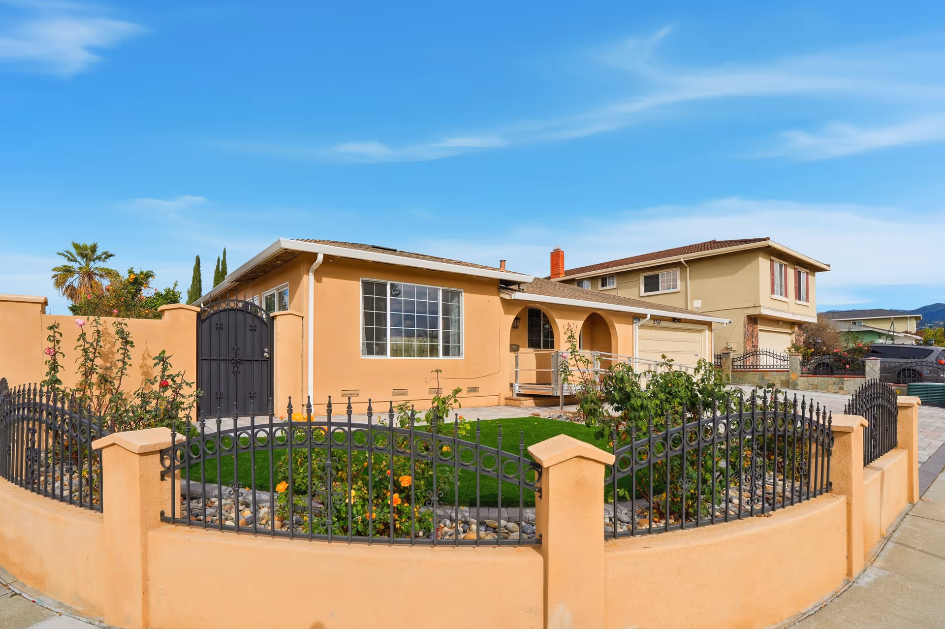 Gated peach-colored senior living facility with arched entry and landscaped front yard