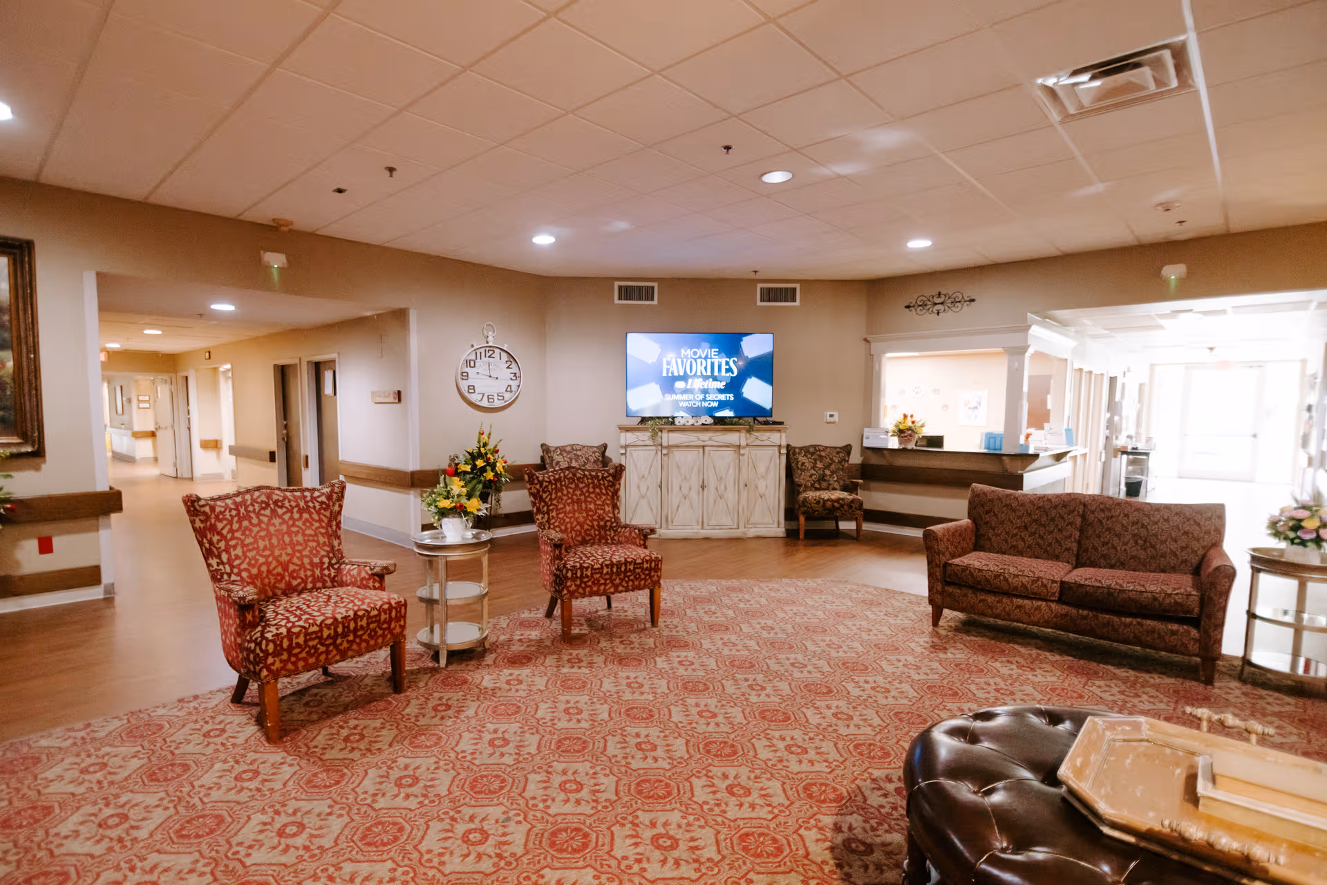Lobby area of a senior facility with sofas, chairs, rug, and a reception desk.