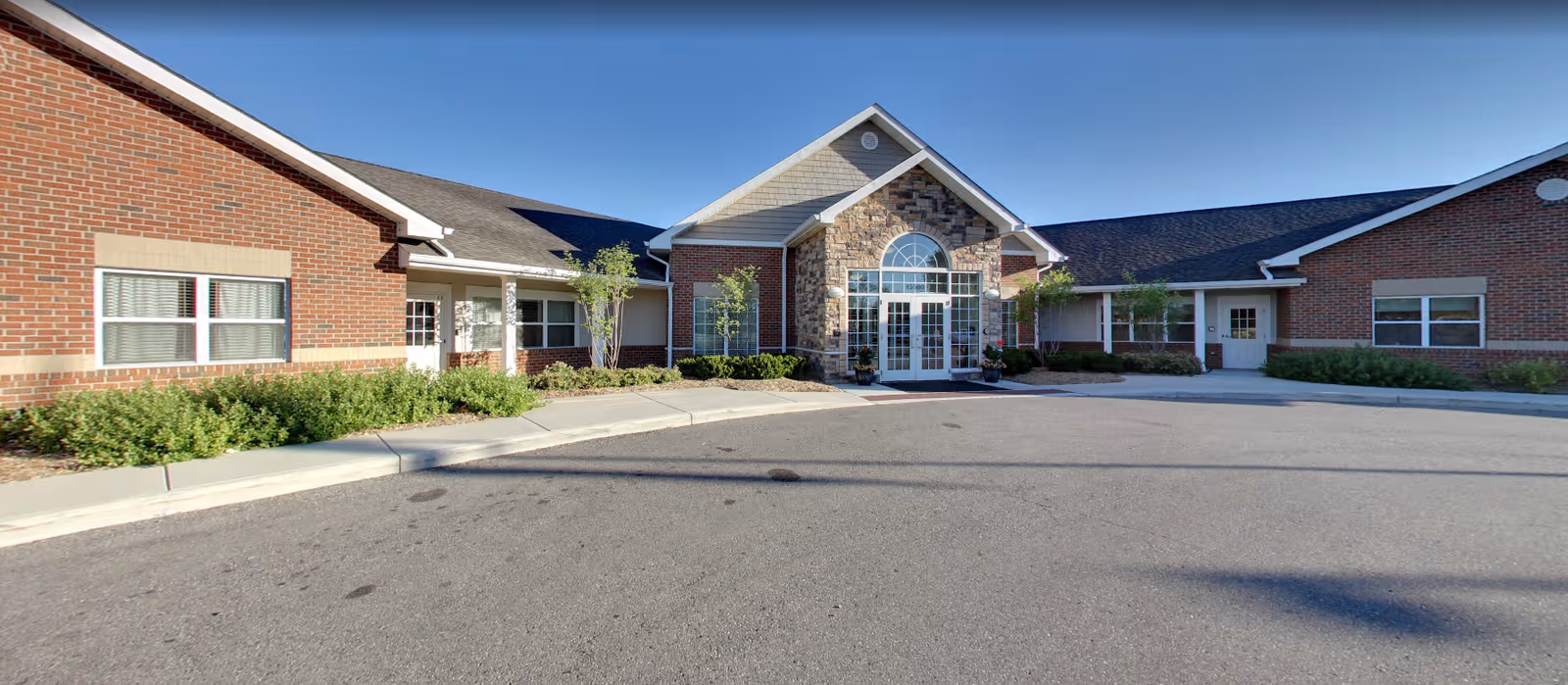 Front exterior of Regency at Canton, brick building with glass entrance and landscaped frontage.