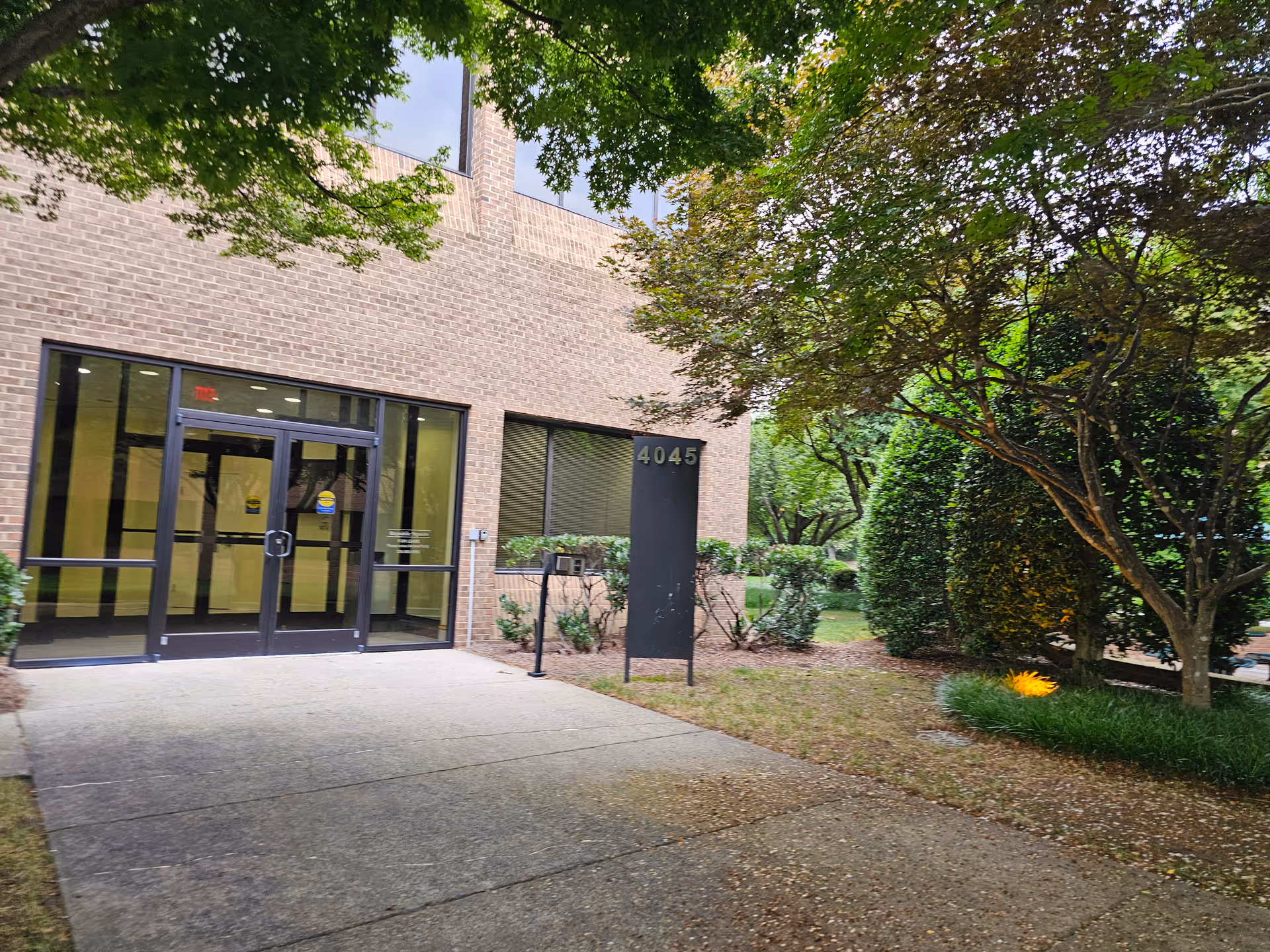 Brick building entrance with glass doors and surrounding trees