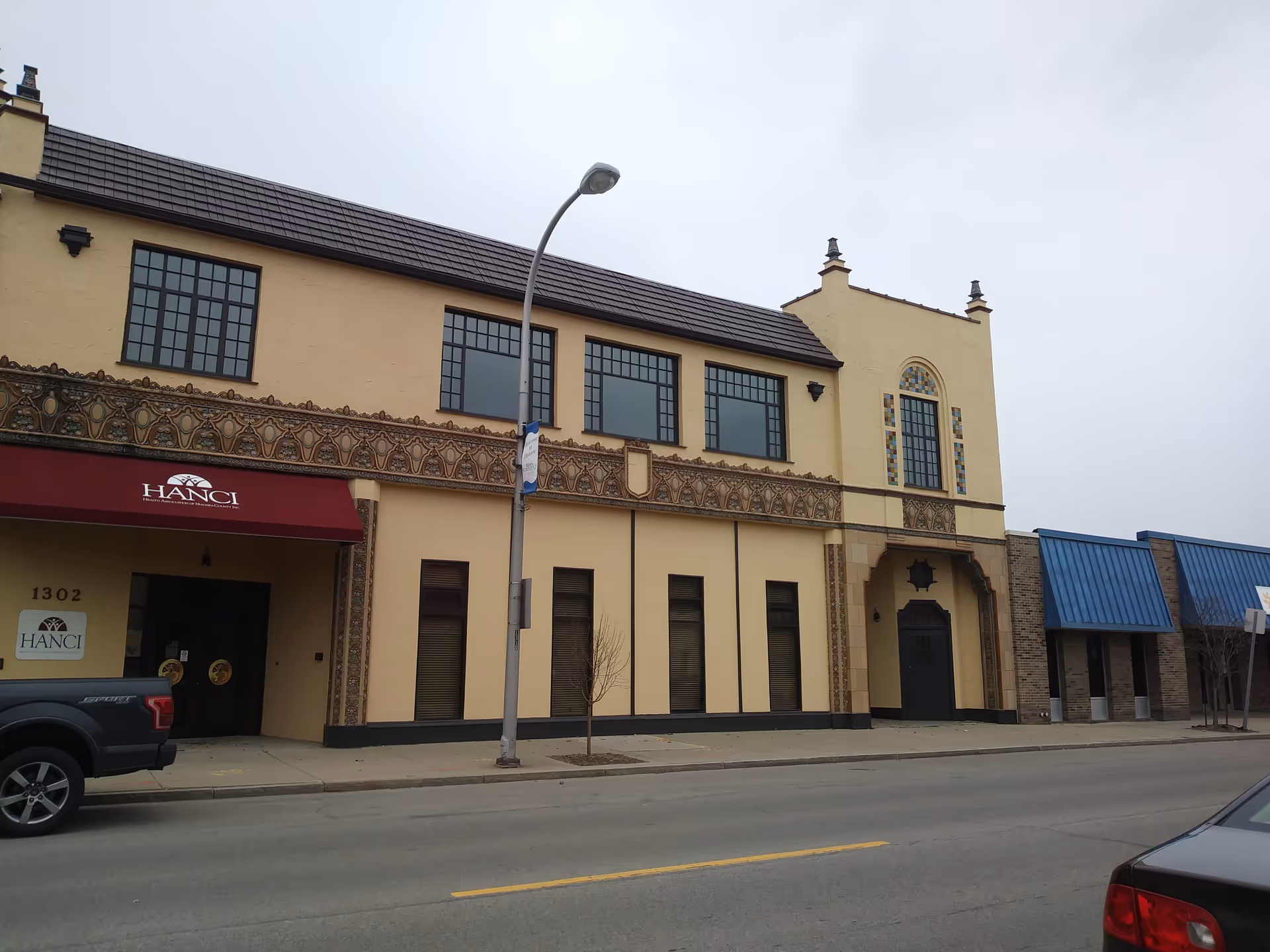 Exterior of a beige building with a red HANCI awning along a street.