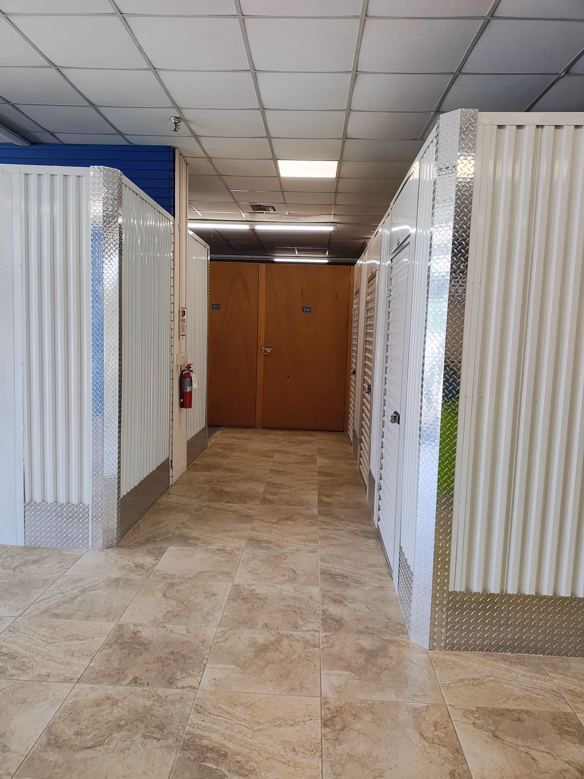 A bright hallway with white storage compartments and wooden doors at the end.