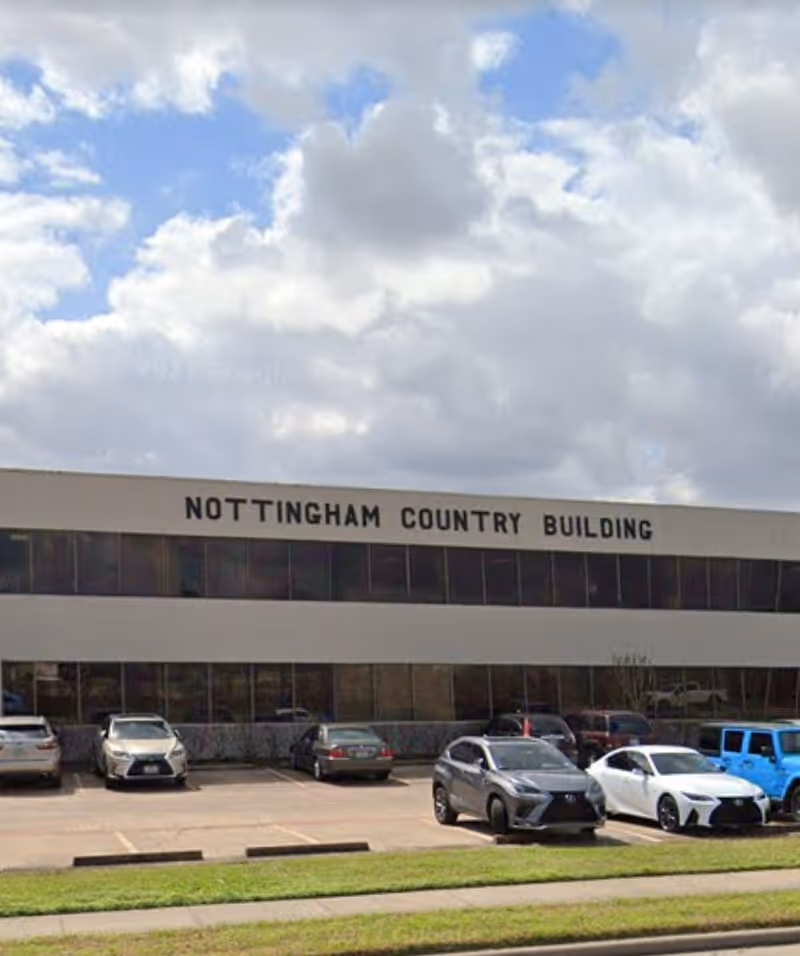 Front view of a building with Nottingham Country Building signage and parked cars.