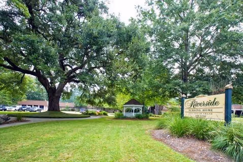 Outdoors with a large tree, gazebo, manicured lawn, and a Riverside sign.