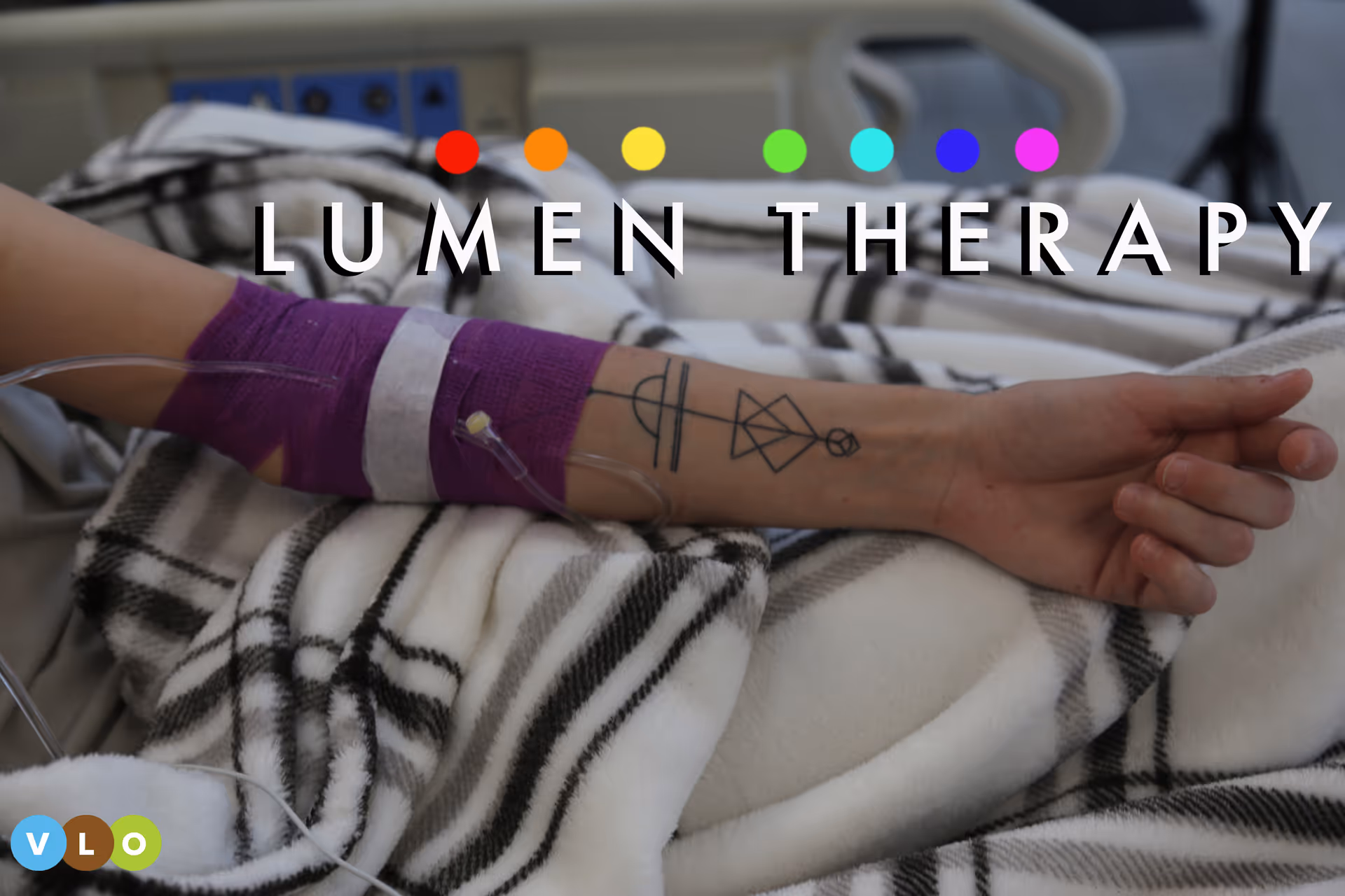 Hospital patient's arm with IV line on bed, wrapped in a purple band.