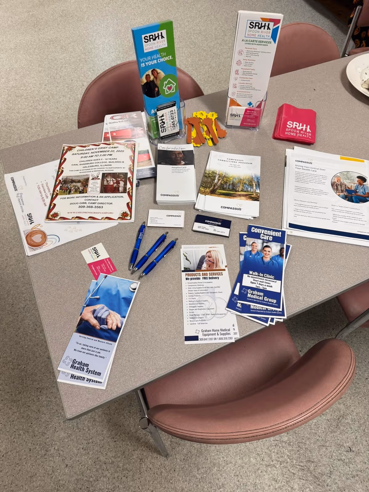 Indoor reception area table with Spoon River Home Health brochures, pens, and pink chairs.