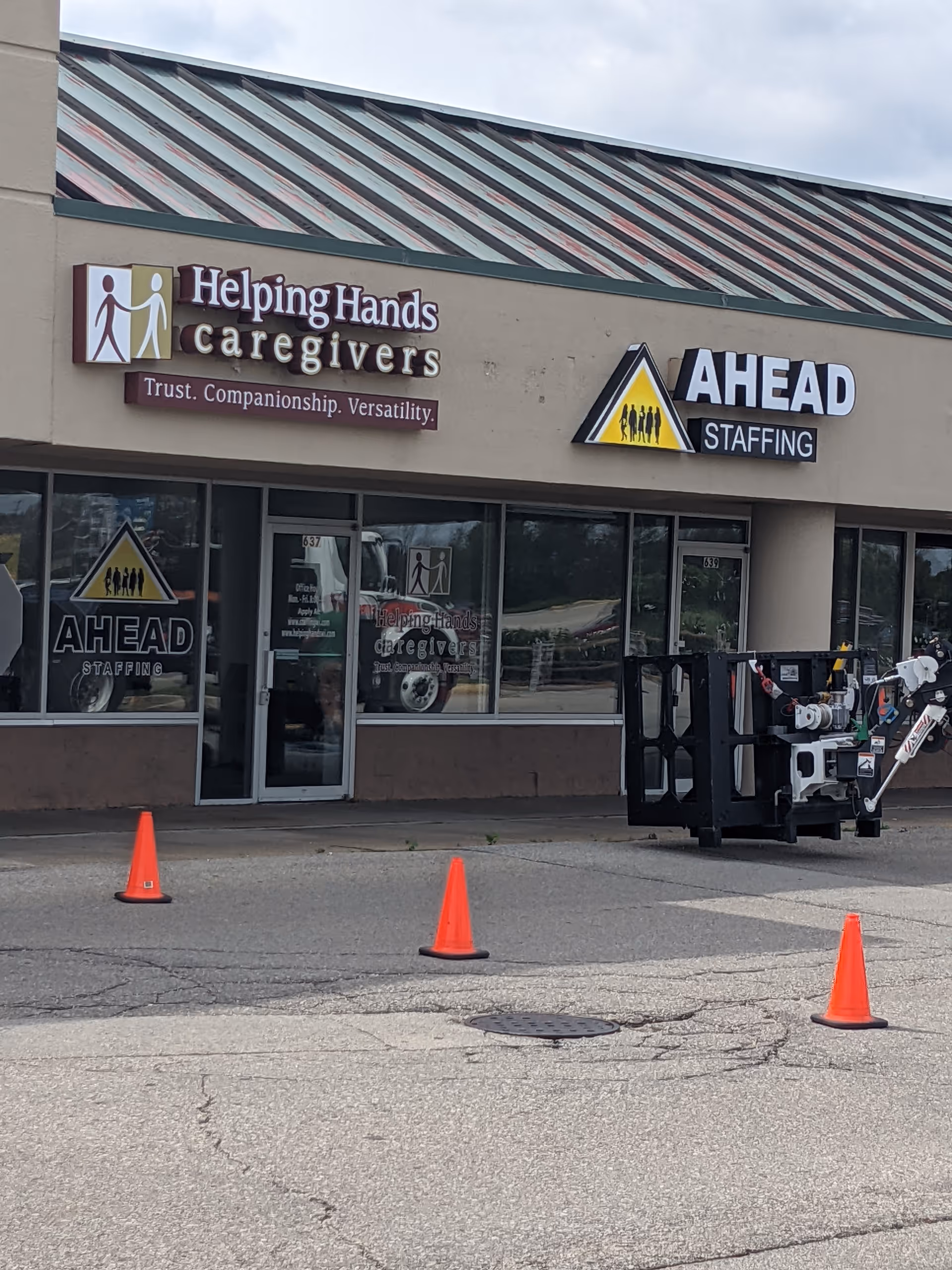 Exterior view of Helping Hands Caregivers storefront with AHEAD Staffing signage and cones.