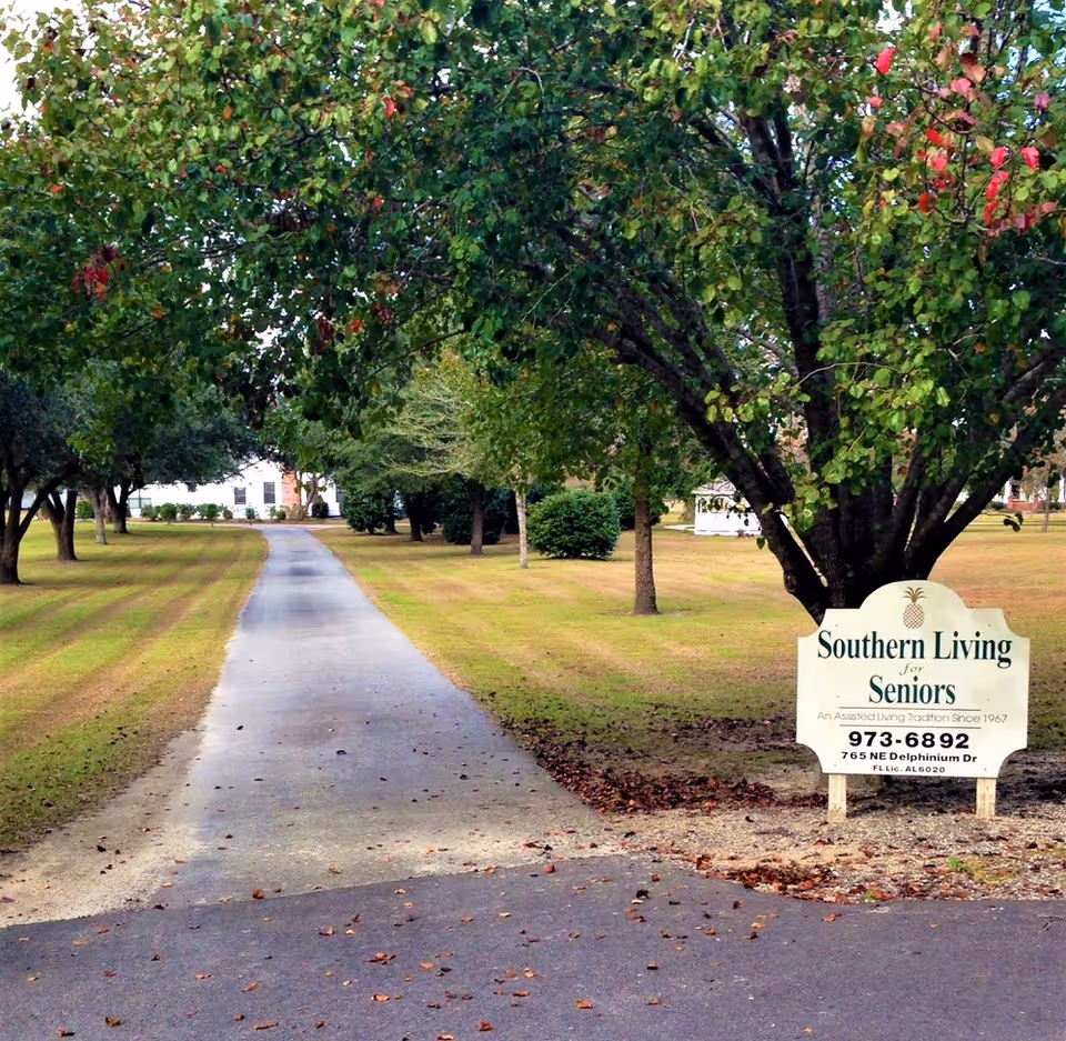 Paved path through lawns and trees toward a Southern Living for Seniors sign.