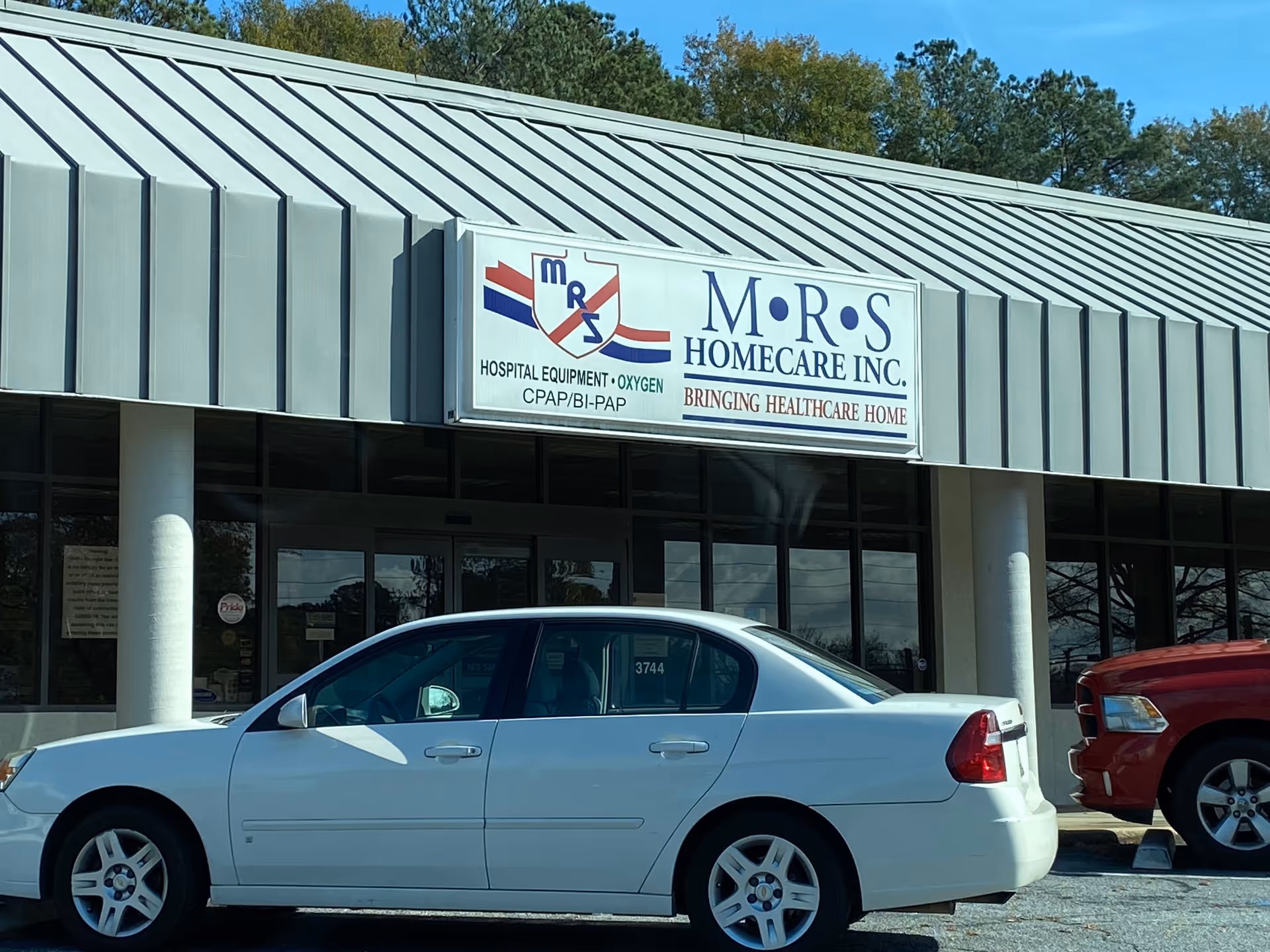 Exterior view of M.R.S. Homecare building with sign and a parked white car.