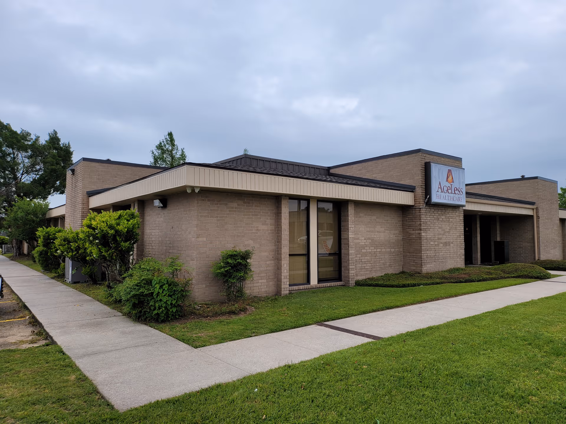 Brick senior living facility exterior with a sidewalk and Ageless Healthcare sign.