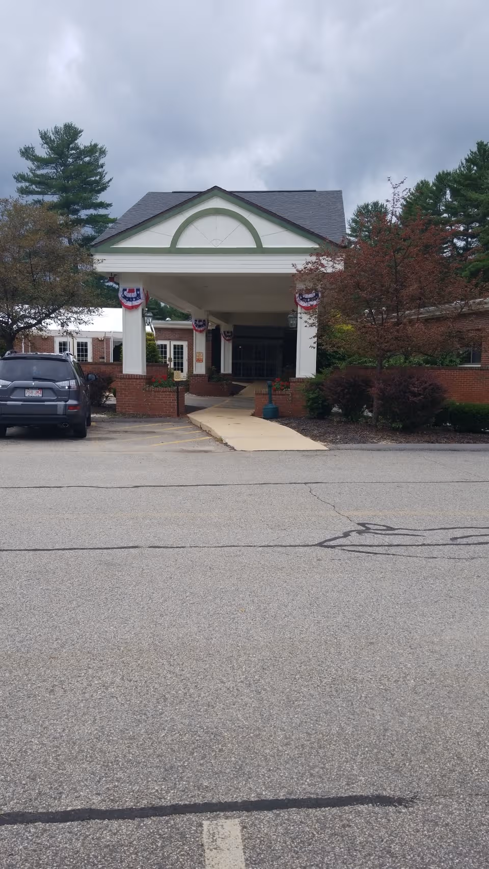 Front entrance of Quabbin Valley Healthcare with bunting, pillars, and a parked SUV.