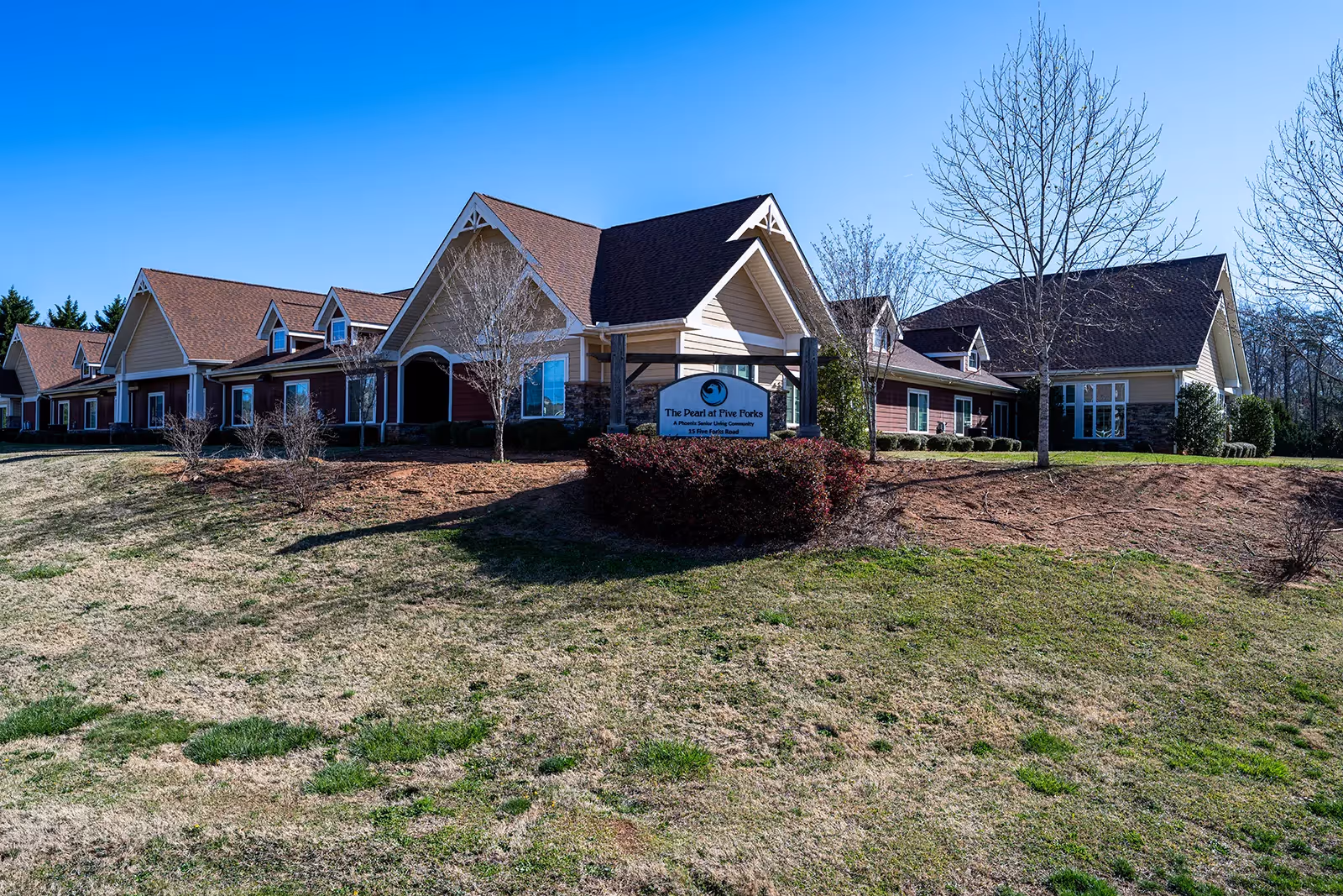 Exterior view of The Pearl at Five Forks, a senior living facility, with sign and landscaping.