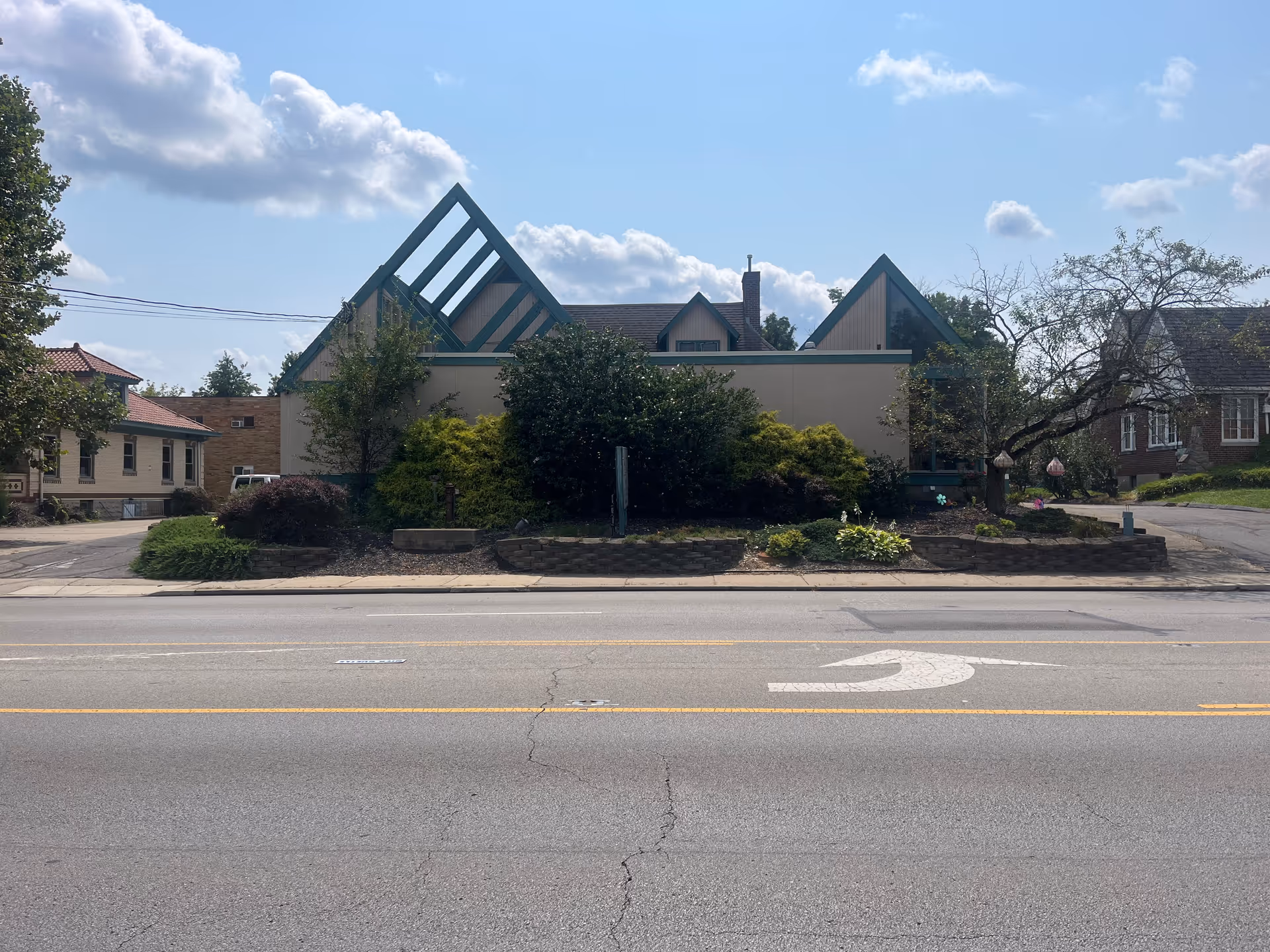 Exterior view of a facility with a distinctive triangular roof and landscaped front yard.